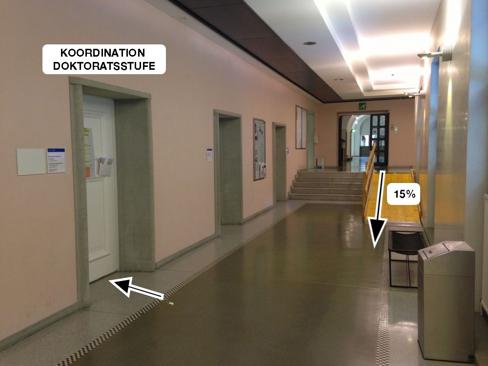 Büro KO2-G-265: Links: Koordination Doktoratsstufe (siehe schwarzer Pfeil).

Von KOL direkt über die Rampe mit 15% Steigung (siehe schwarzer Pfeil) gelangt man zur Koordination Doktoratsstufe.

Es existieren auch indirektere Wege zum Büro mit flacheren Rampen. Sehen Sie hierfür die generellen Angaben zum Stockwerk F und G.