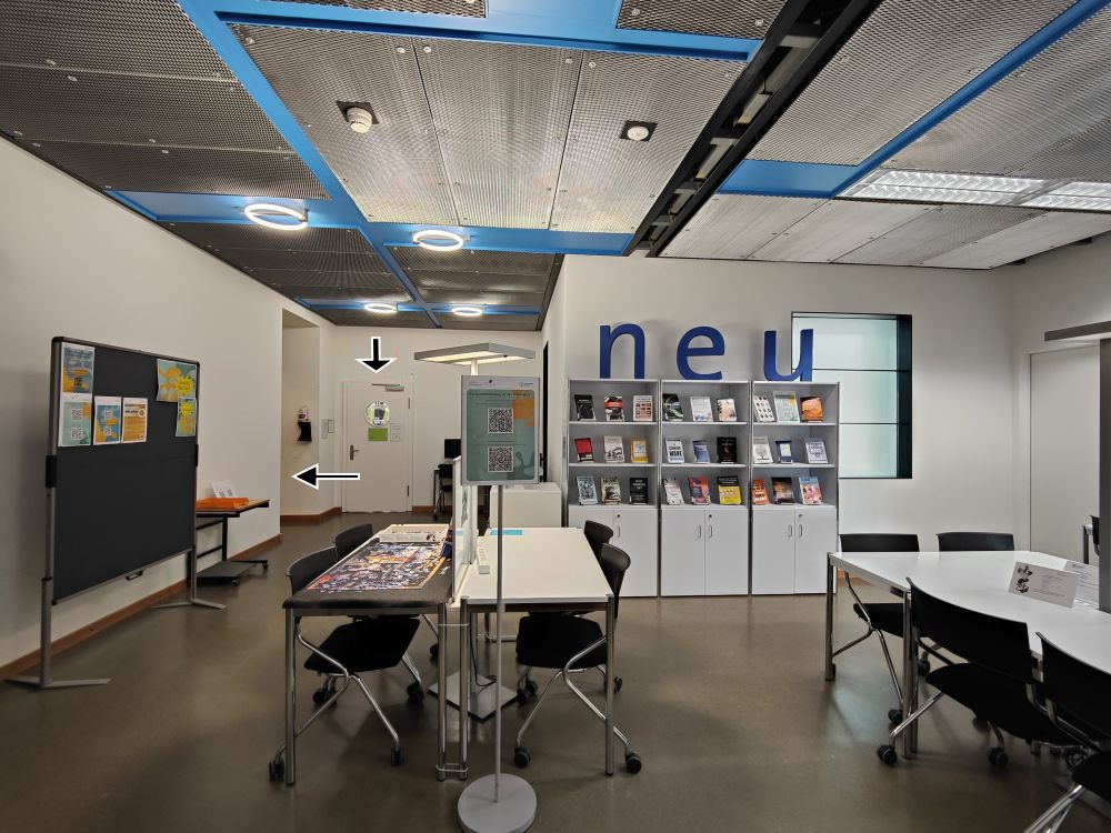 Arbeitsraum für Studierende KOL-H-303c: Foyer mit 14 Arbeitsplaetzen vom Eingang aus gesehen. Hinten links fuehrt die Tuer mit rundem Fenster zum Lesesaal, im Gang links daneben befindet sich der Lift Ost. Rechts um die Ecke (nicht im Bild) ist der Zugang zum Kopierraum.