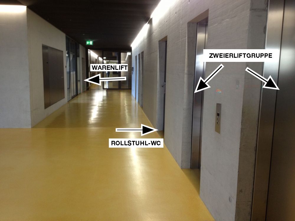 Rollstuhl-WC TKK-00-61: Das RS-WC befindet sich links neben der Zweierliftgruppe (Pfeile).