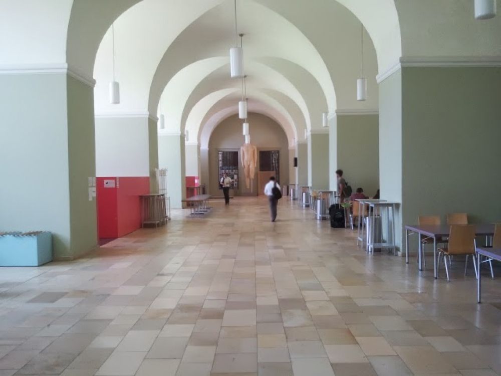 KOL, Stockwerk D: Aufenthaltshalle für Studierende (Foyer West) unterhalb des Lichthofs; Zugriff auf Zeitungen sowie Arbeitsplätze mit Strom und LAN-Anschluss sind vorhanden.