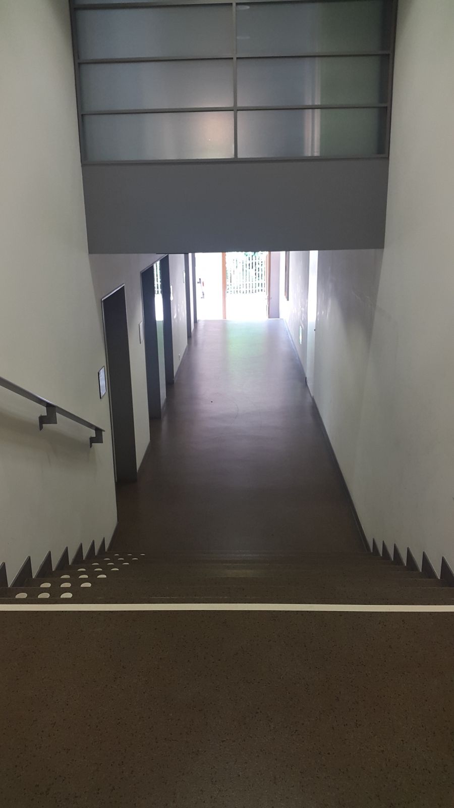 KOL, Stockwerk Ea: Nach dem Eingang zum KOL-E-49 mit Blick nach rechts. Treppe mit Handlauf und Bodenmarkierung. Auf der liken Seite (zweite Türe) befindet sich die Türe die zum Zwischenstockwert KOL-Ea.
