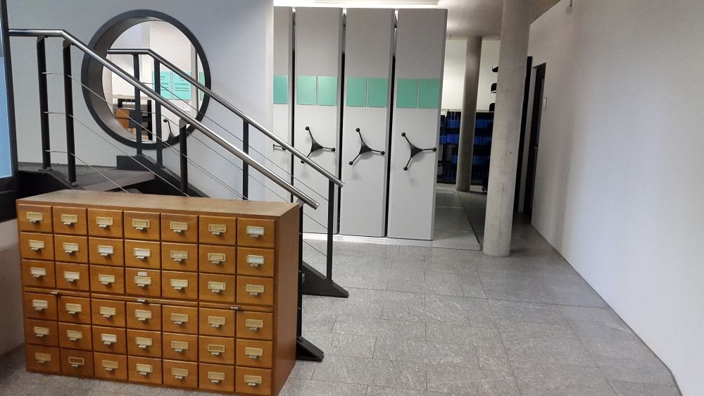 ZUB-U, Bibliothek: Blick vom Eingang aus auf die rechte Seite des Raumes. Die Treppe fürht zu Büros des Instituts.