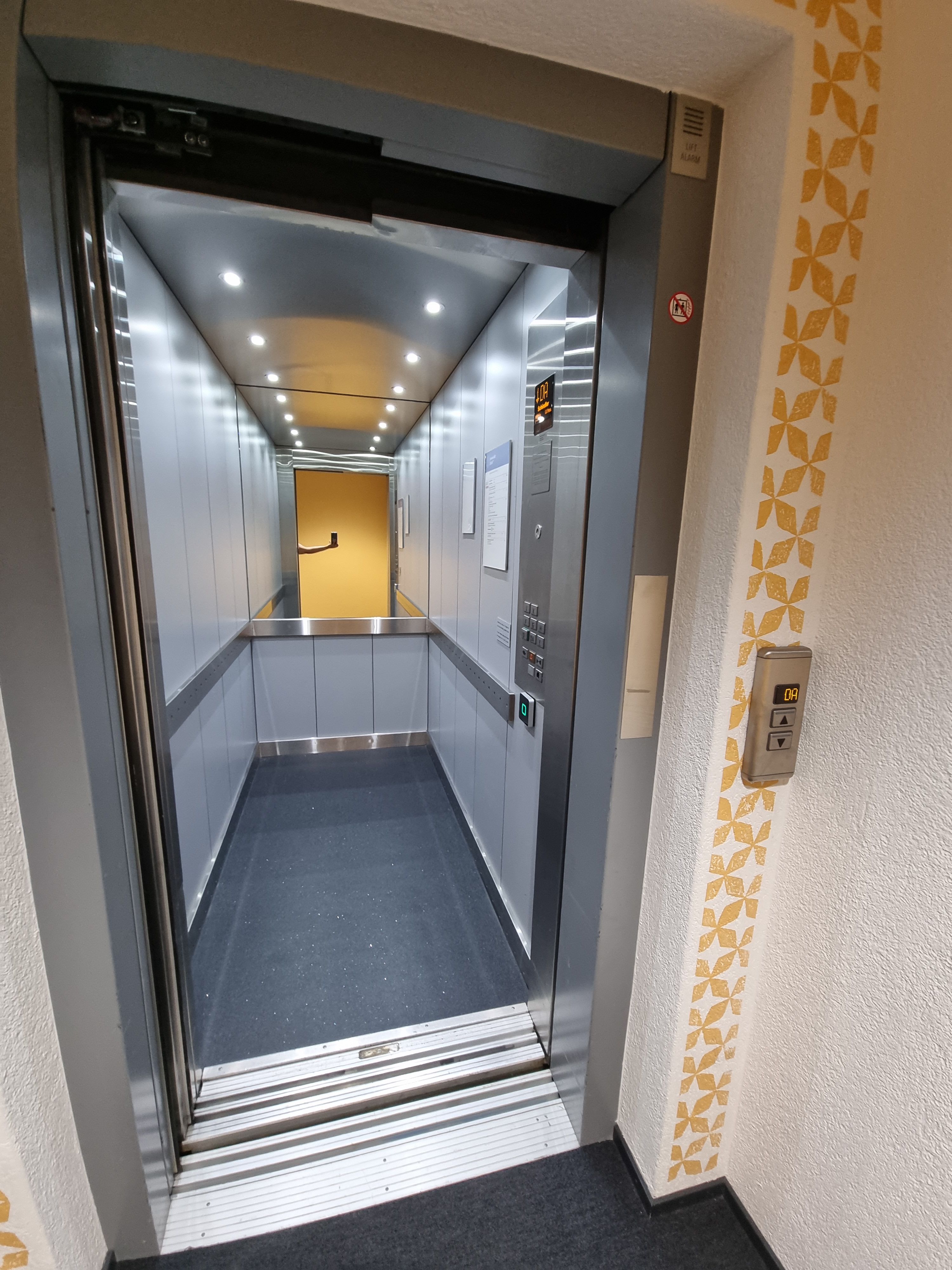 Da 928: Foto vom Lift von Aussen. Die Tasten sind auf der rechten Seite ausserhalb und innerhalb des Lifts. Die Liftwand gegenüber des Lifteingangs ist verspiegelt. Das Foto wurde auf dem Stockwerk Da geschossen.