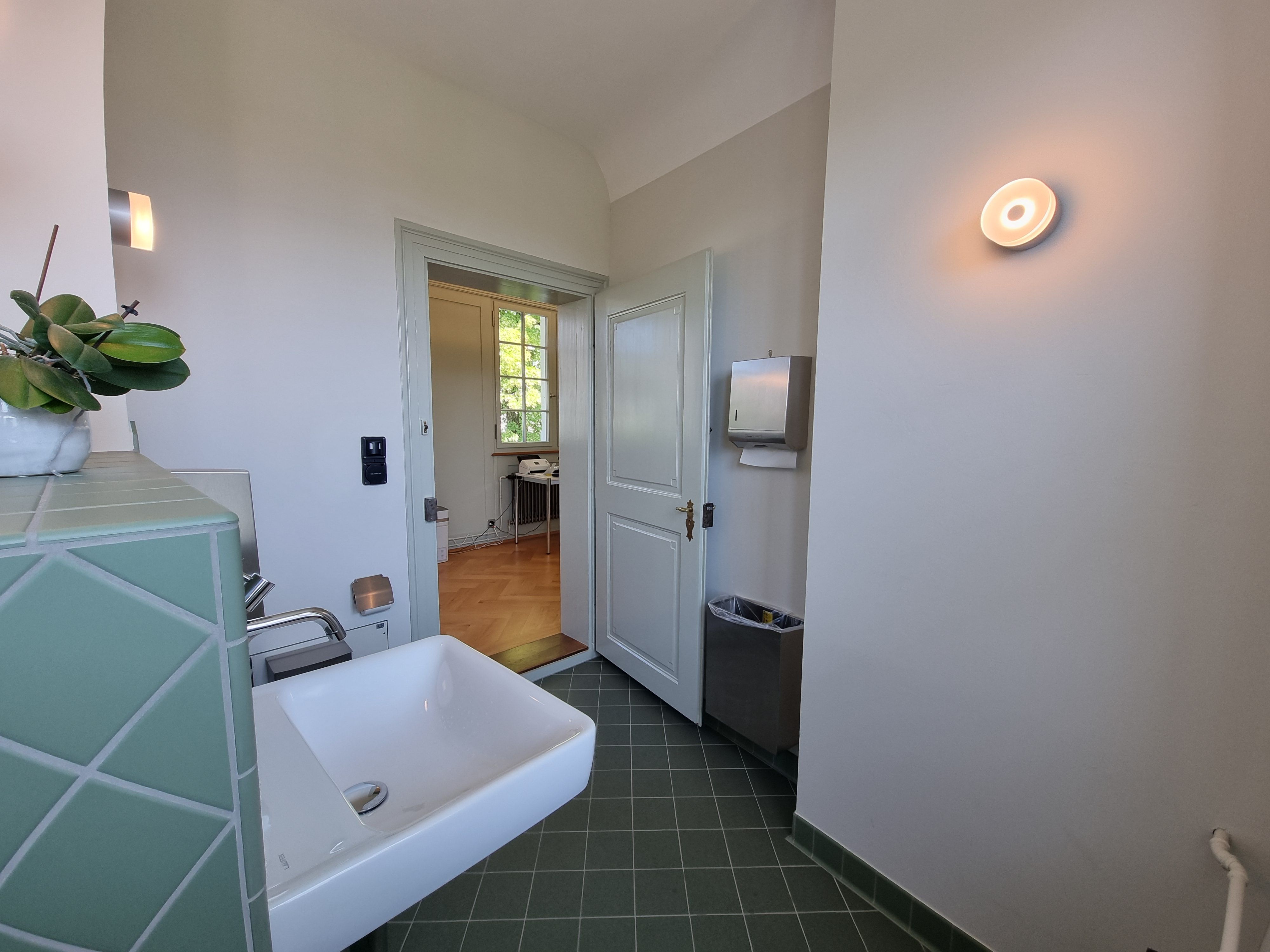 G-108: Bild des WCs vom Fenster aus betrachtet. Die Einganstür ist offen. Man erkennt die 7cm hohe Schwelle.