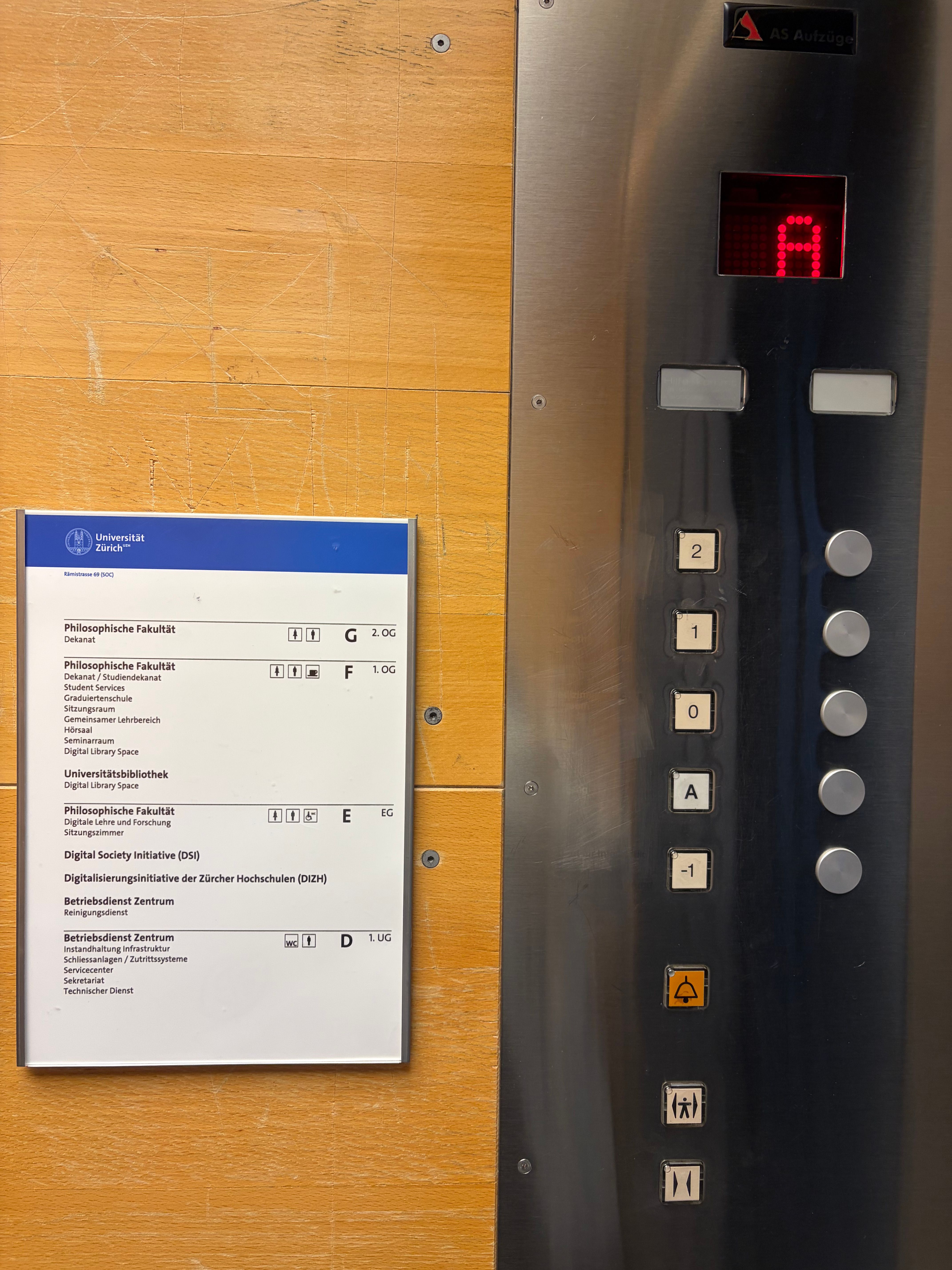 SOC, Lift: Lifttastatur und die dazugehörige Legende. -1 entspricht dem Stockwerk D.  A entspricht dem Liftausgang direkt ins Freie. 0 entspricht dem Stockwerk E. 1 entspricht dem Stockwerk F. 2 entspricht dem Stockwerk G.