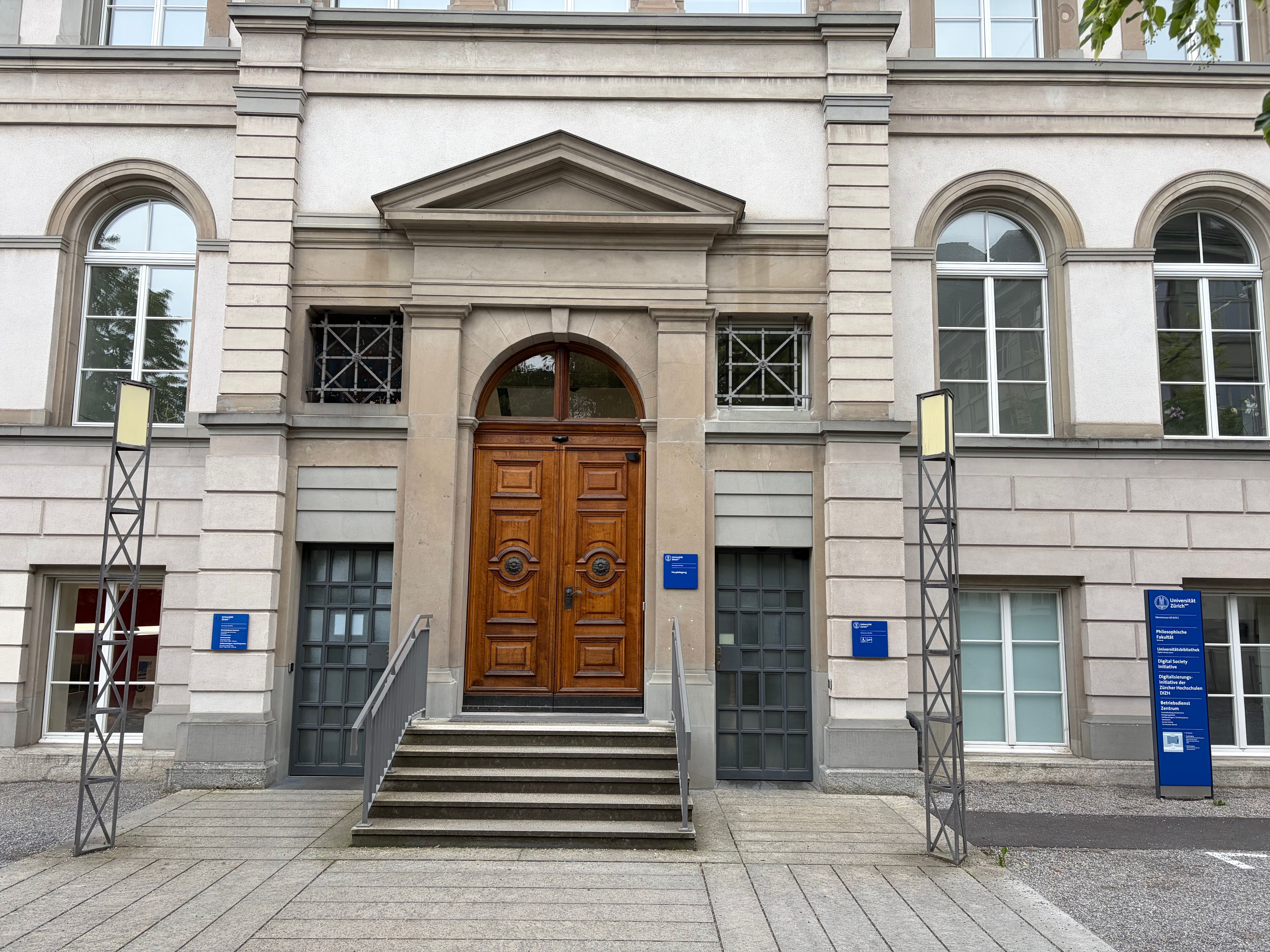Haupteingang des Gebäudes SOC. 
Links: Eingang Betriebsdienst Zentrum (für stufenlosen Zugang Lift zum Stockwerk -2 benutzen).
Mitte: Haupteingang (Nach der Tür folgt eine weitere Treppe bis zum Stockwerk E).
Rechts: Alternativer Eingang für stufenlosen Zugang direkt zum Lift.