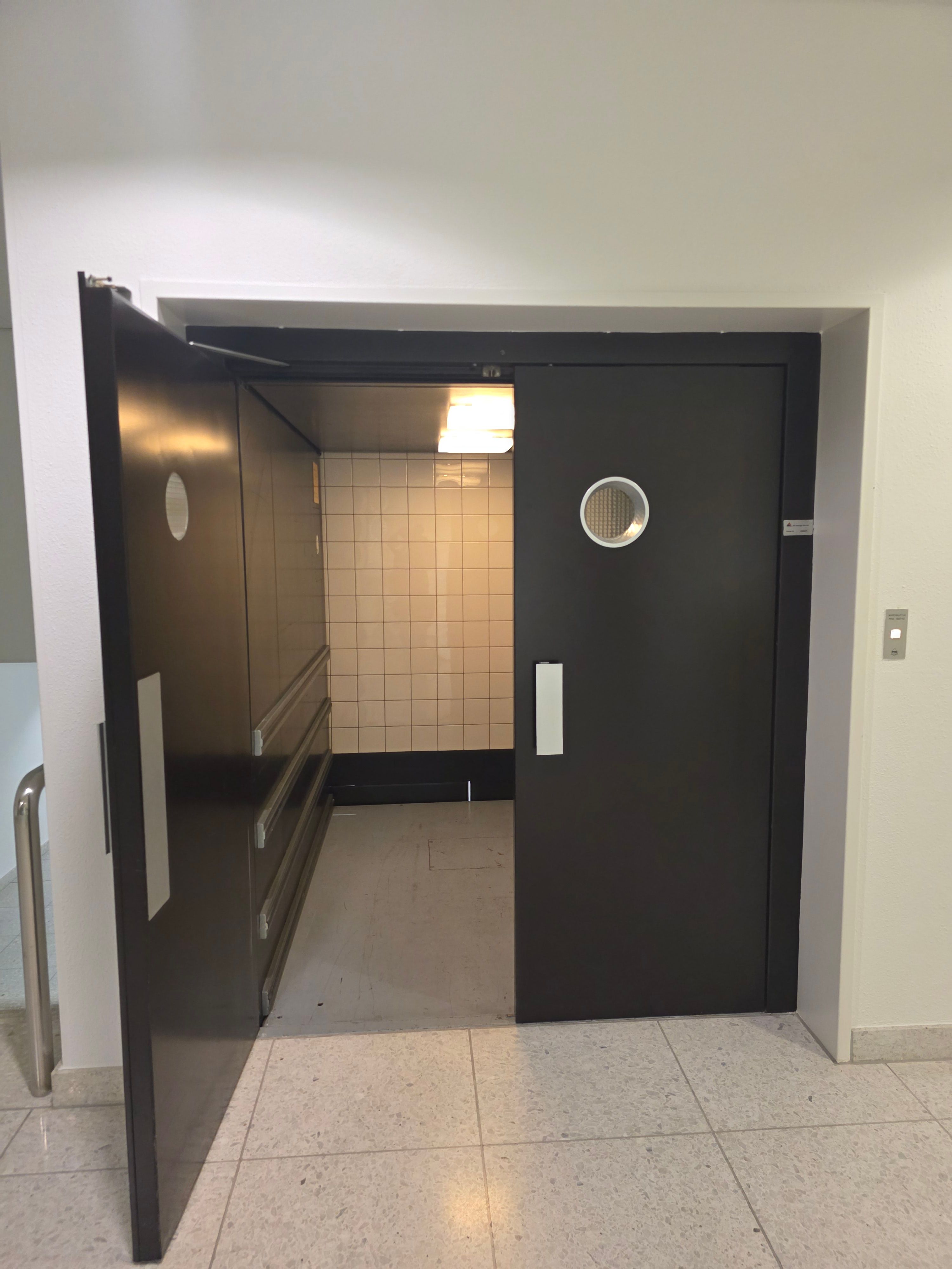 Y01, Warenlift zu den Computerräumen: Der linke Türflügel des Lifts ist geöffnet und man sieht den Innenraum. Die rechte Tür muss von jemanden aufgehalten werden, da sie sonst zufällt.