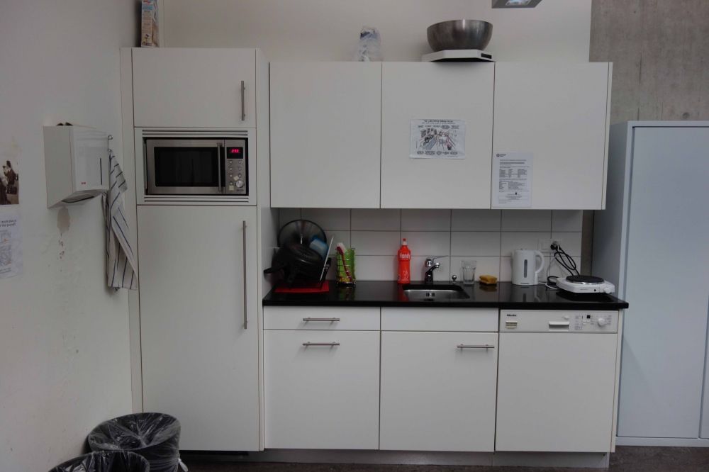 Aufenthaltsraum AND-2-11: Küchen-Nische der AI Lounge. Von links nach rechts: Mikrowelle (oben) und Kühlschrank (unten), Lavabo, Wasserkocher, Herdplatte. Der Erste-Hilfe-Kasten befindet sich an der linken Wand (nicht im Bild).