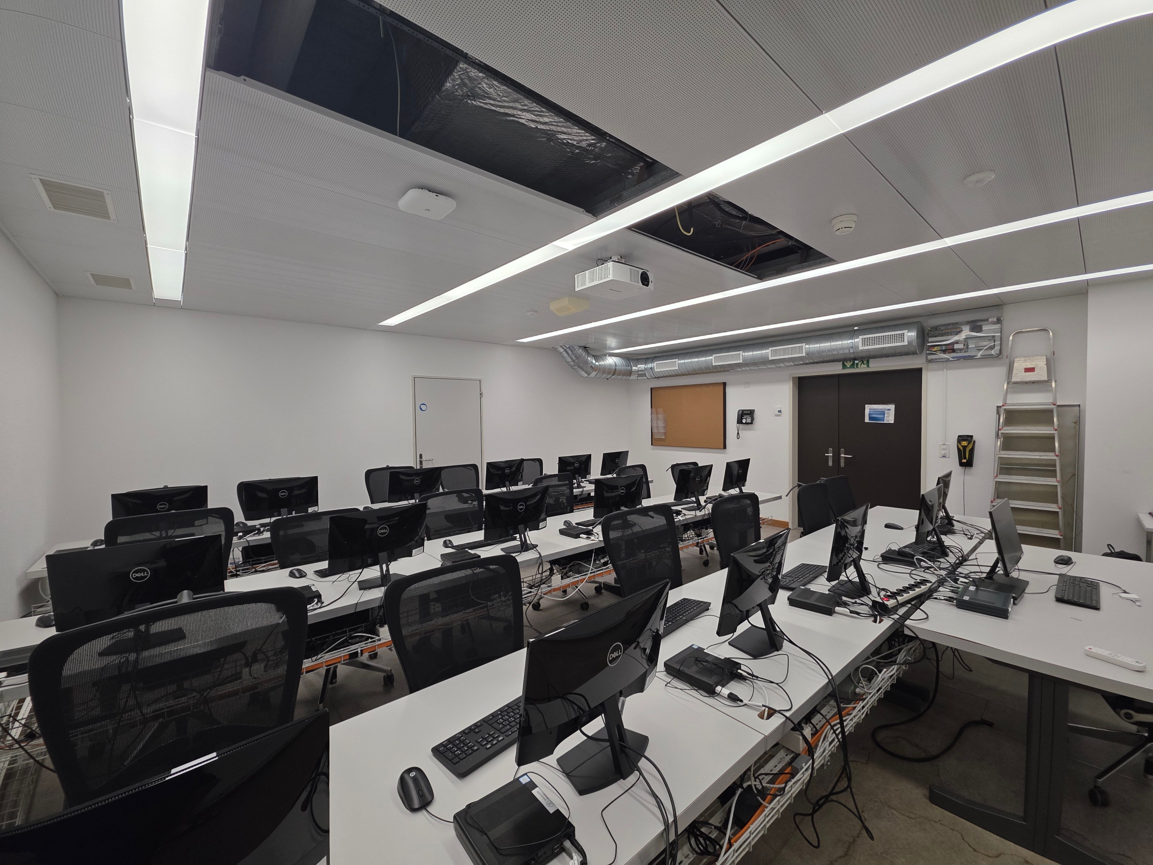 Computerkurs-Raum Y01-F-08: Blick auf den Raum von der Wandseite gegenüber der Tür, mit Blick auf die Eingangstür.