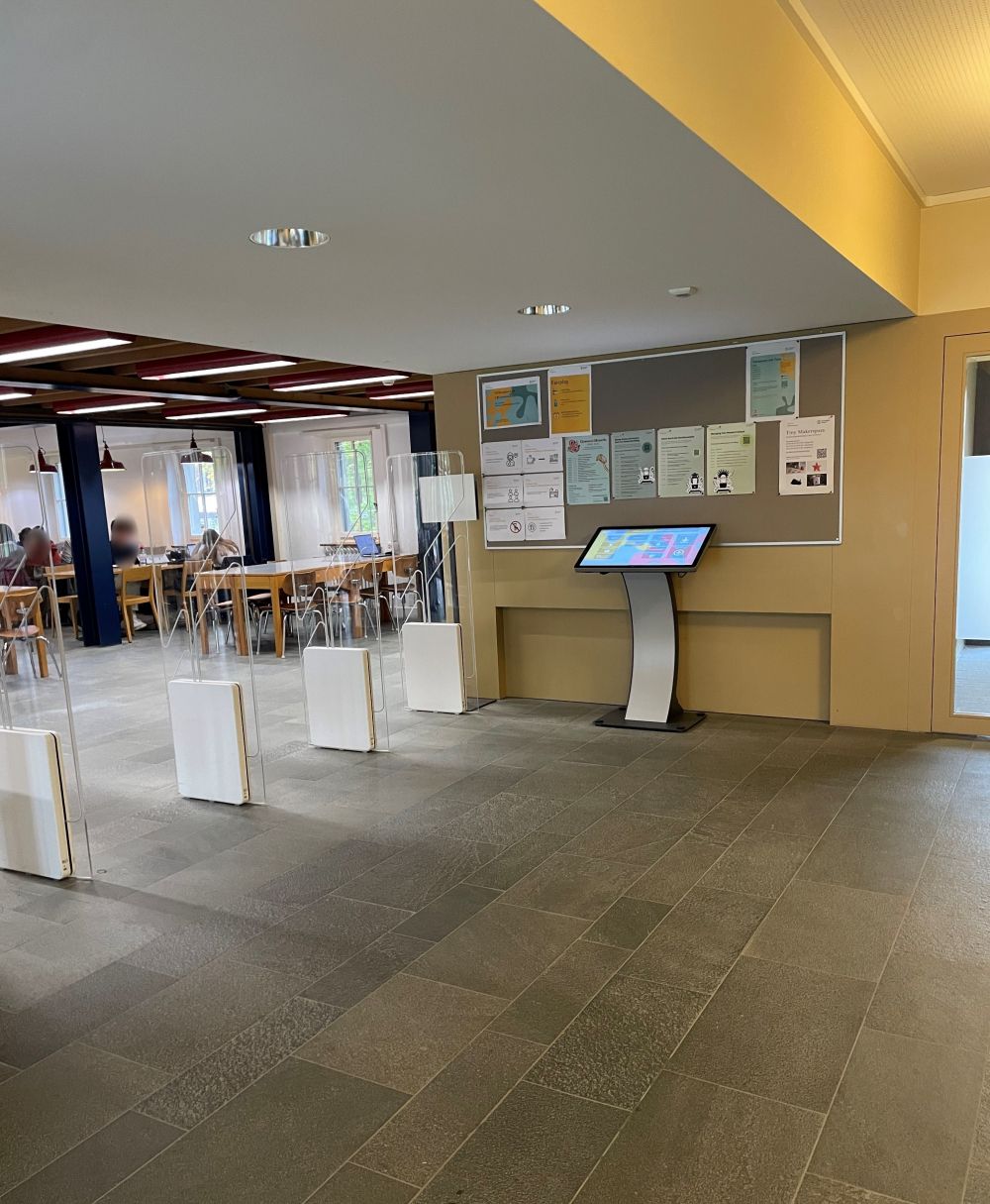 Y63-E, Bibliothek: Rechts die Pinwand, davor das Kioskterminal, links Kontrollschranken der ehemaligen Bibliothek in den Aufenthaltsraum E-03.