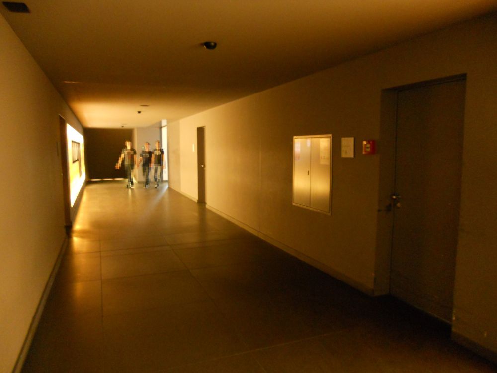 Gebäude MEN: Auf dem Weg vom KOL zu den Mensen:
- Ganz rechts auf dem Foto: Küchentüre, der zum Küchenlift führt (relevanter Weg zur unteren Mensa A für Rollstuhlfahrende; siehe auch Angaben bei Lift).
- Am Ende des Korridors rechts: obere Mensa B.
- Am Ende des Korridors geradeaus: Treppen hinunter zur Mensa A.