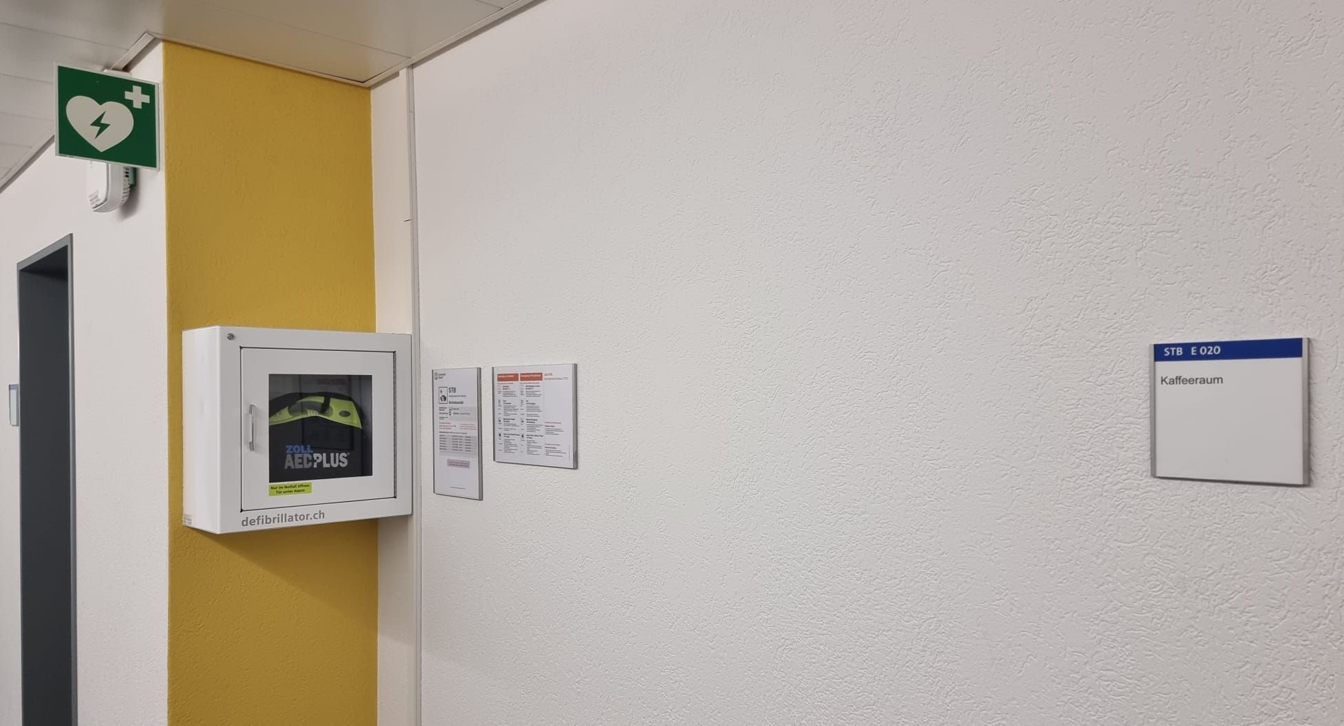 STB Gebäude: Das Bild zeigt den Standort des Defibrillators. Der Defibrillator ist links an der Wand montiert, neben dem Kaffeezimmer E 020.