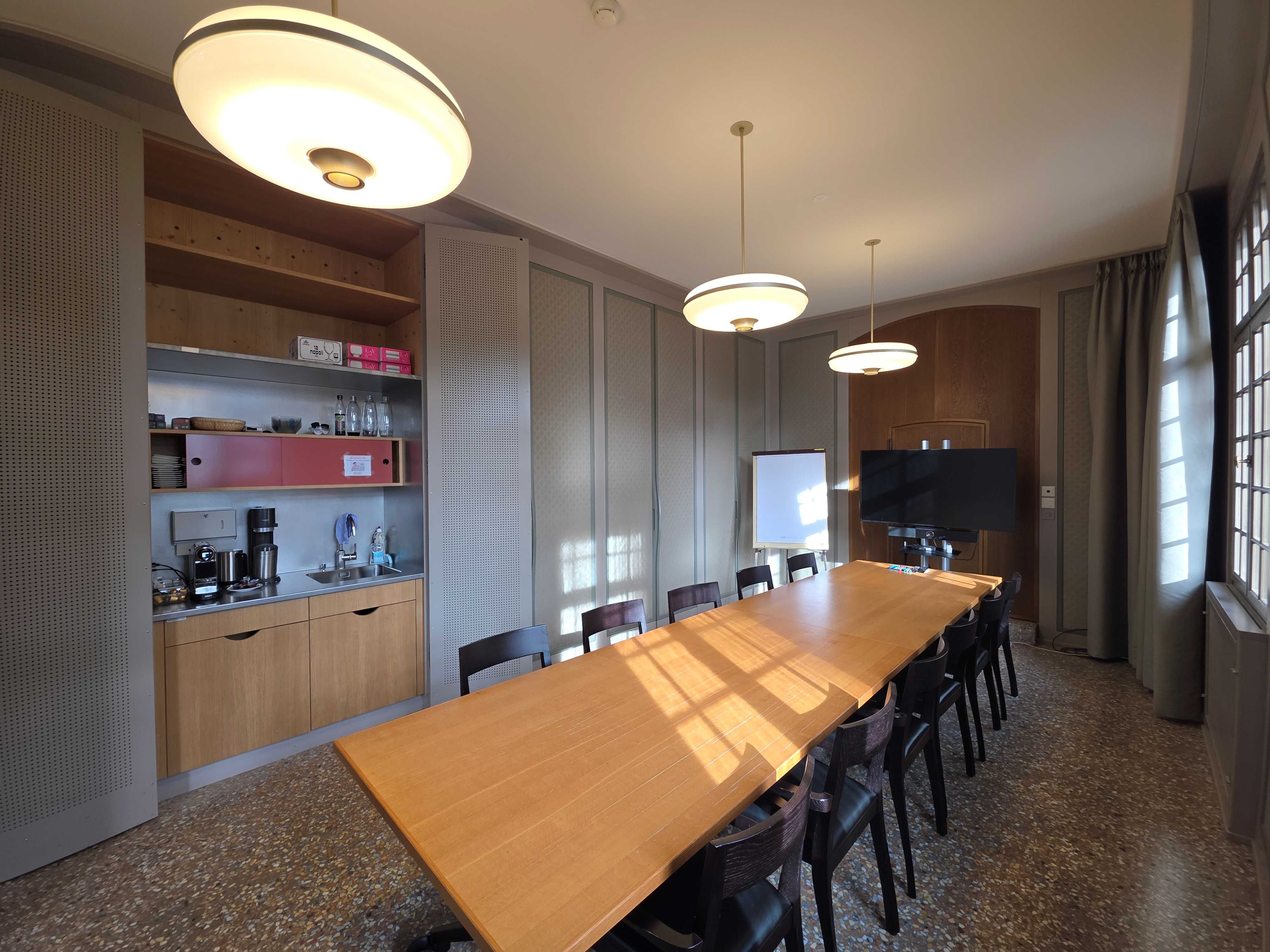 E-03: Blick auf den ganzen Raum von der rechten Zimmerecke neben dem Eingang. Der Raum hat eine kleine Teeküche auf der linken Seite hinter den Schranktüren.