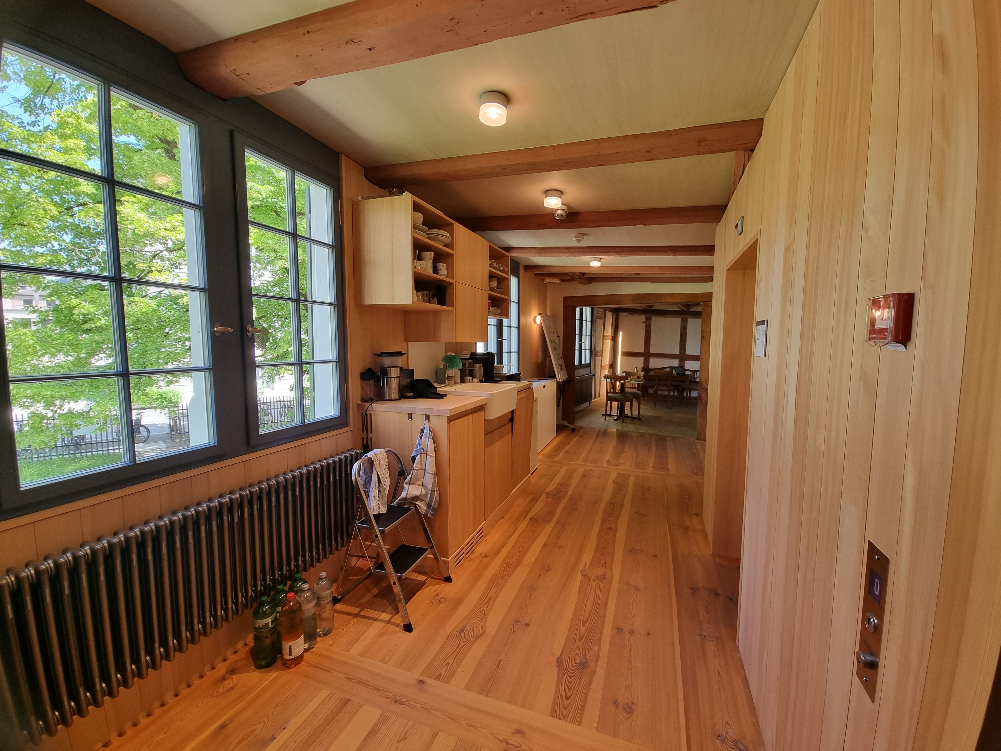 SOB 1. Stock: Bild vom Gang nach Verlassen des Lifts. Die Tür vorne auf der rechten Seite führt zum WC mit einem Pissoir und einer Sitztoilette. Auf der linken Seite sieht man die Teeküche des Stockwerks.