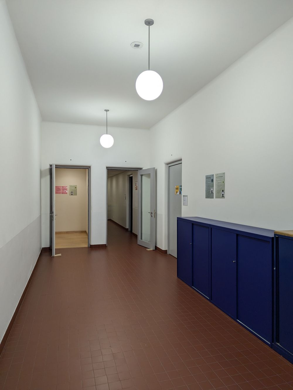 Rollstuhl-WC RAI-BIB-L-115: Blick nach links nach Passieren der weissen Tür. Der Gang in der Mitte führt zum Rollstuhl-WC.