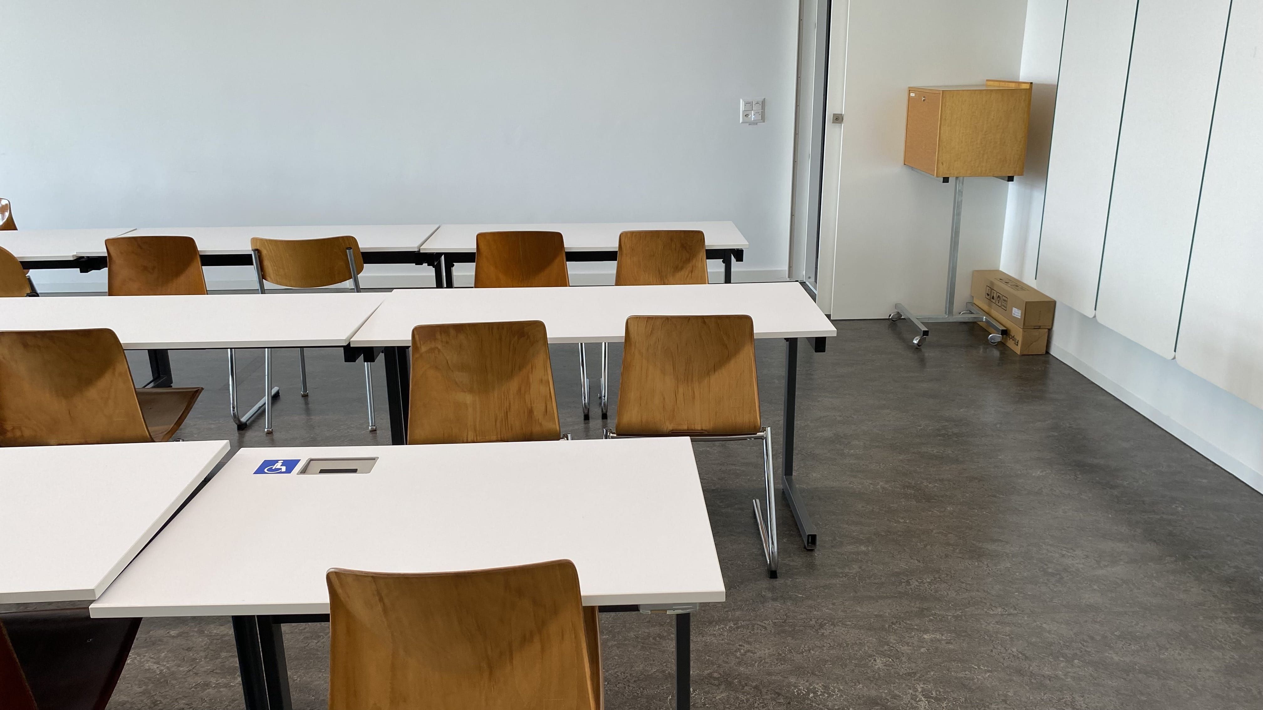 Seminarraum RAI-J-031: Ansicht auf den Tisch mit Rollstuhl-Signet. Der Tisch befindet sich in der dritten Reihe von vorne, in der Nähe der Eingangstüre.