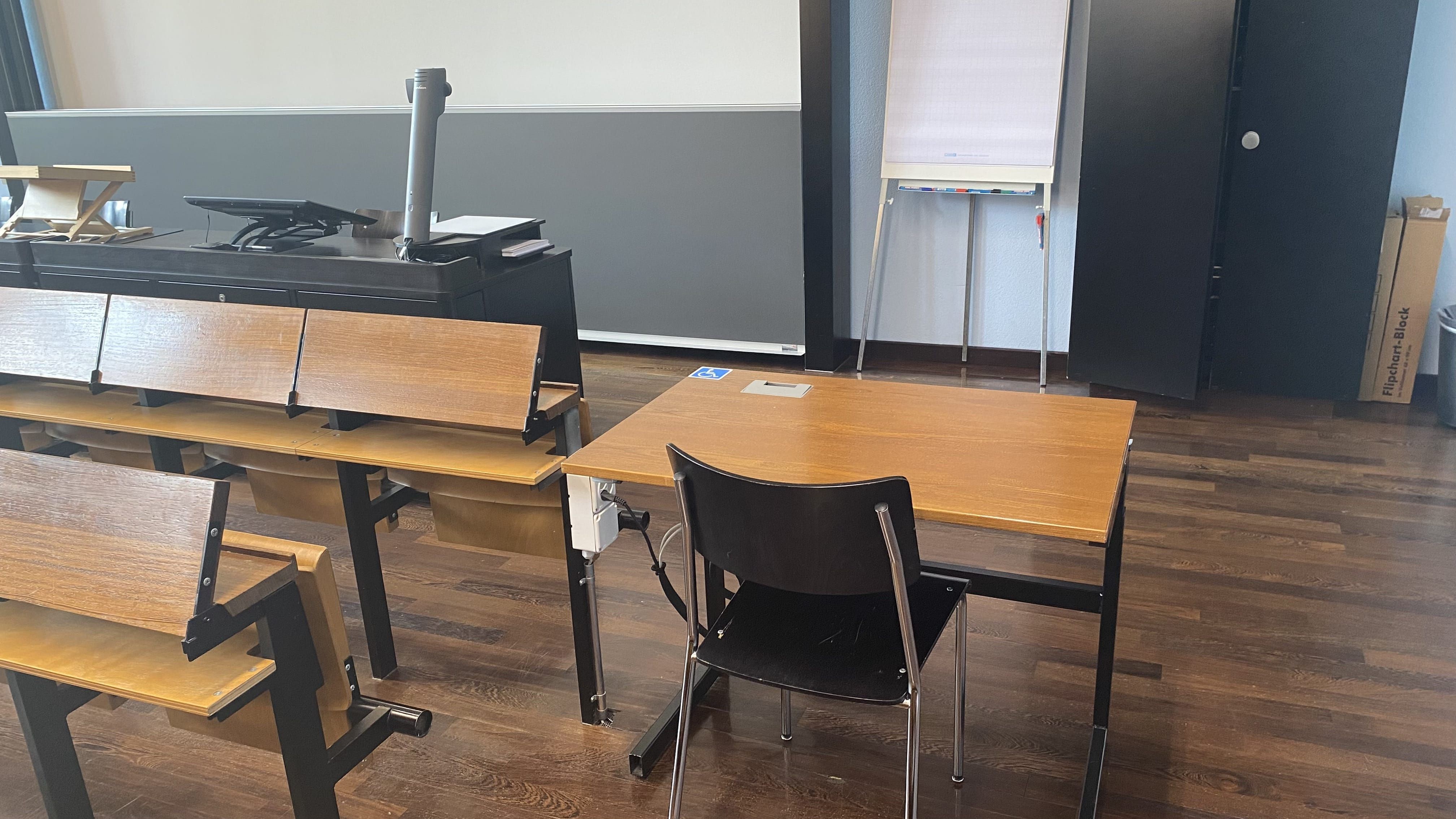 Hörsaal KOL-F-118: Ansicht auf den zweiten elektrisch höhenverstellbaren Tisch mit Rollstuhl-Signet. Dieser Tisch befindet sich in der vordersten Reihe rechts im Raum, nahe der Eingangstür.
