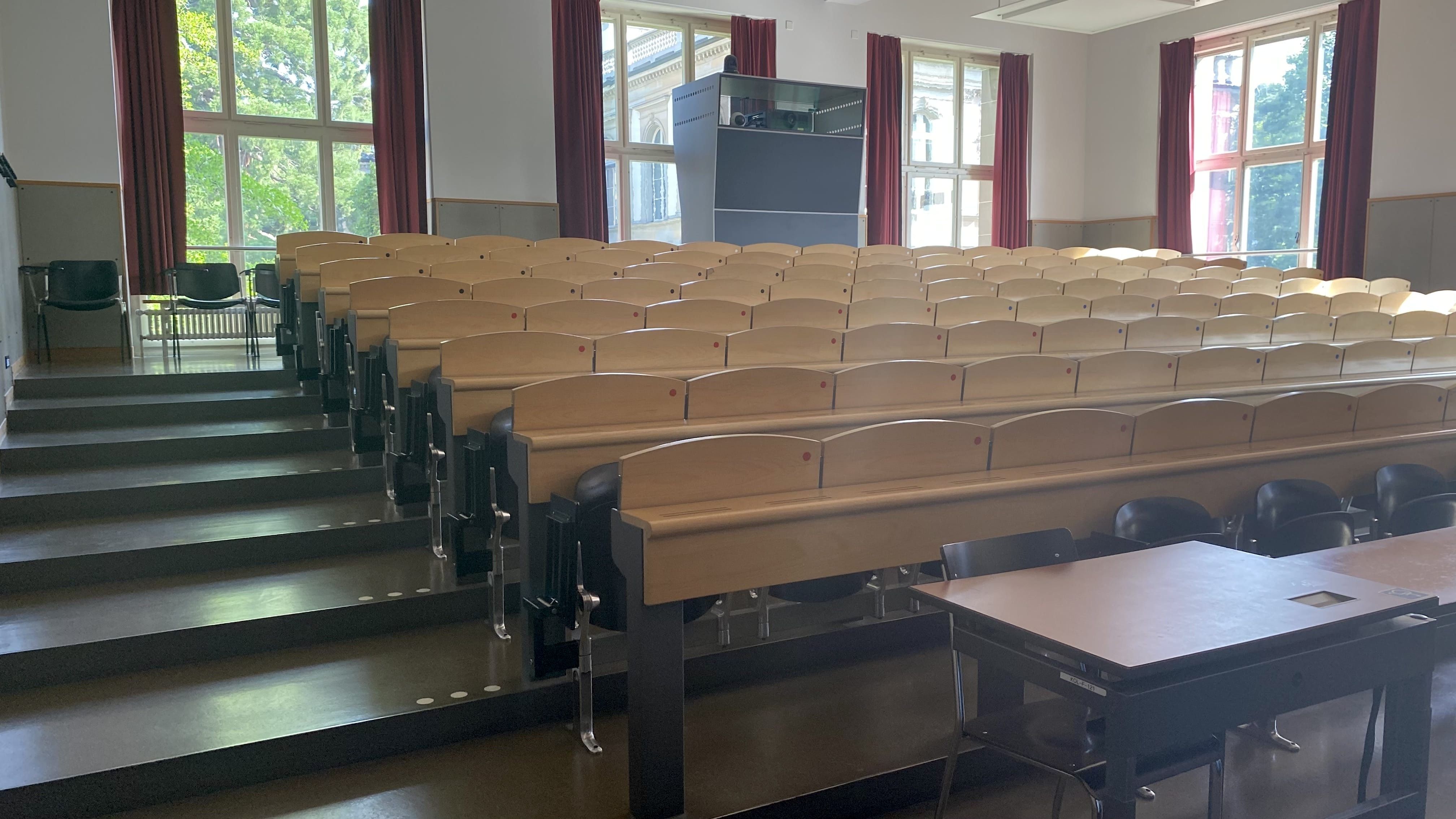 Hörsaal KOL-F-121: Ansicht auf den Raum von der Eingangstür aus. Die breiten Stufen links sind mit Orientierungshilfen markiert.