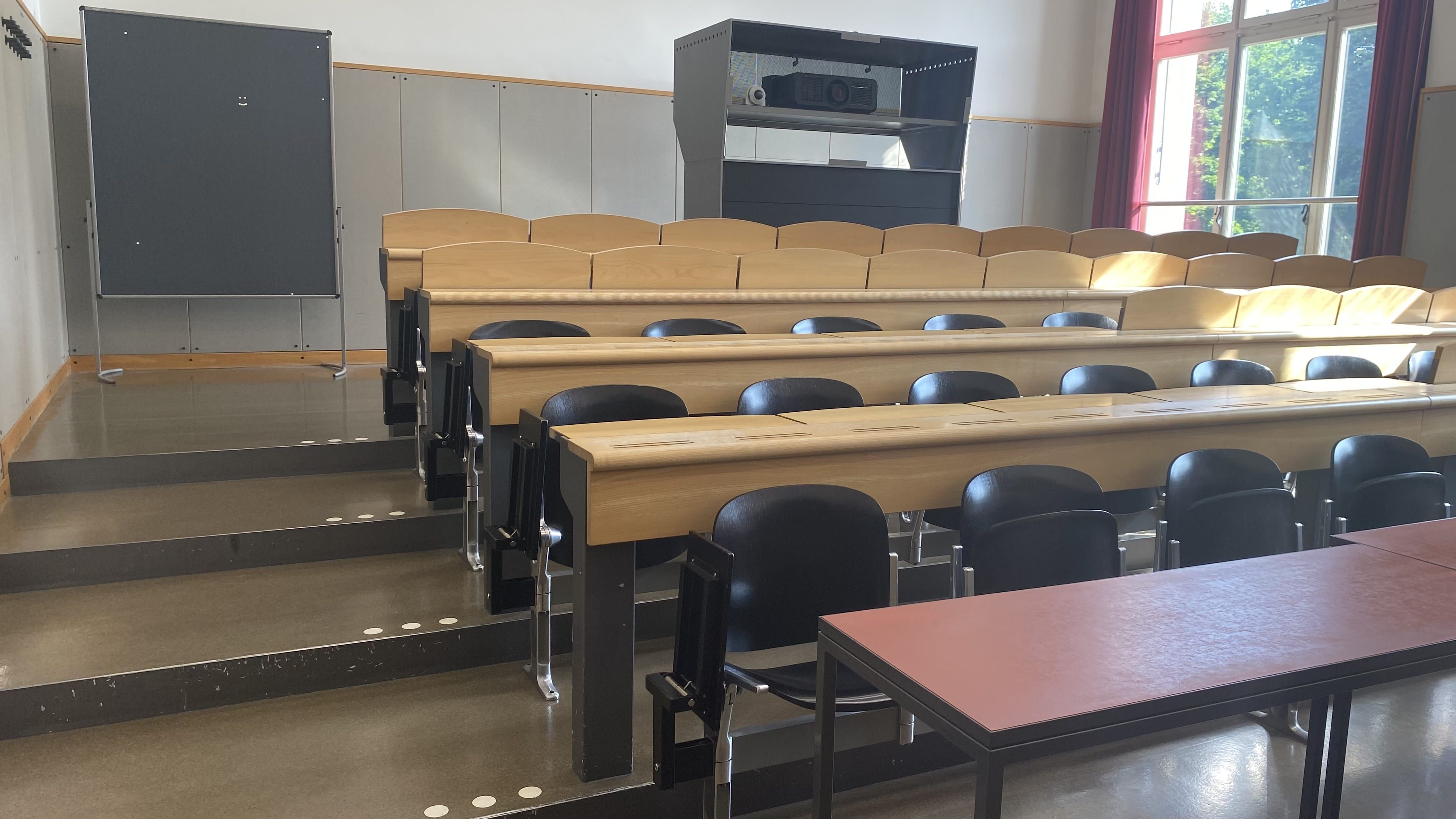 Hörsaal KOL-F-123: Ansicht auf den Raum von der Eingangstür aus. Die breiten Stufen links sind mit Orientierungshilfen markiert.