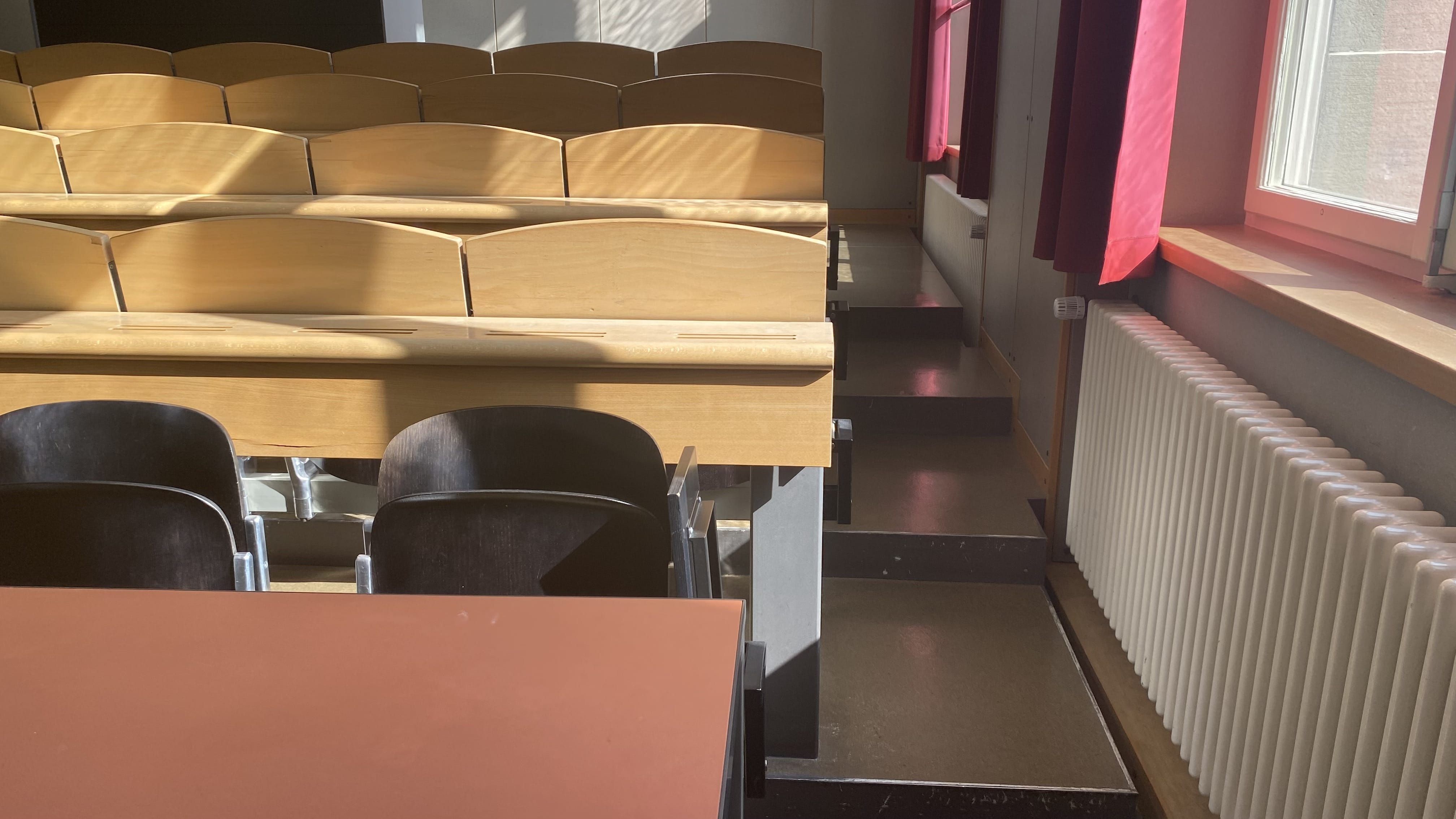 Hörsaal KOL-F-123: Ansicht auf den schmalen Durchgang auf der rechten Seite des Raumes. Die schmalen Stufen sind nicht mit Orientierungshilfen markiert.