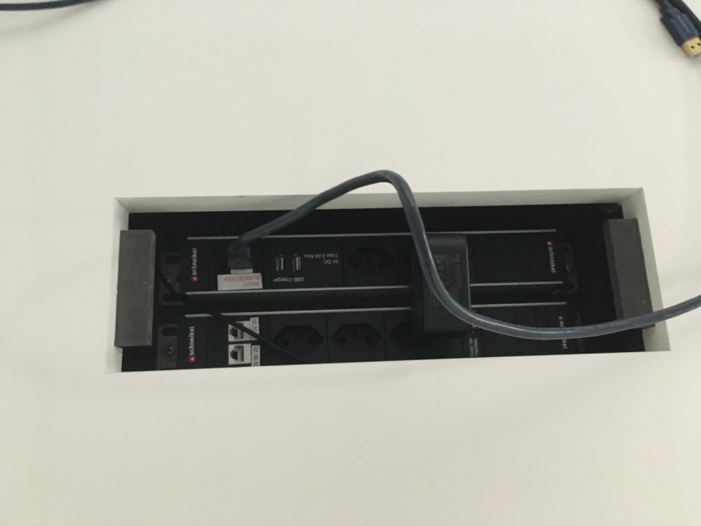 Sitzungsraum PLR-H-111: Diverse Steckdosen in der Mitte des Tisches.