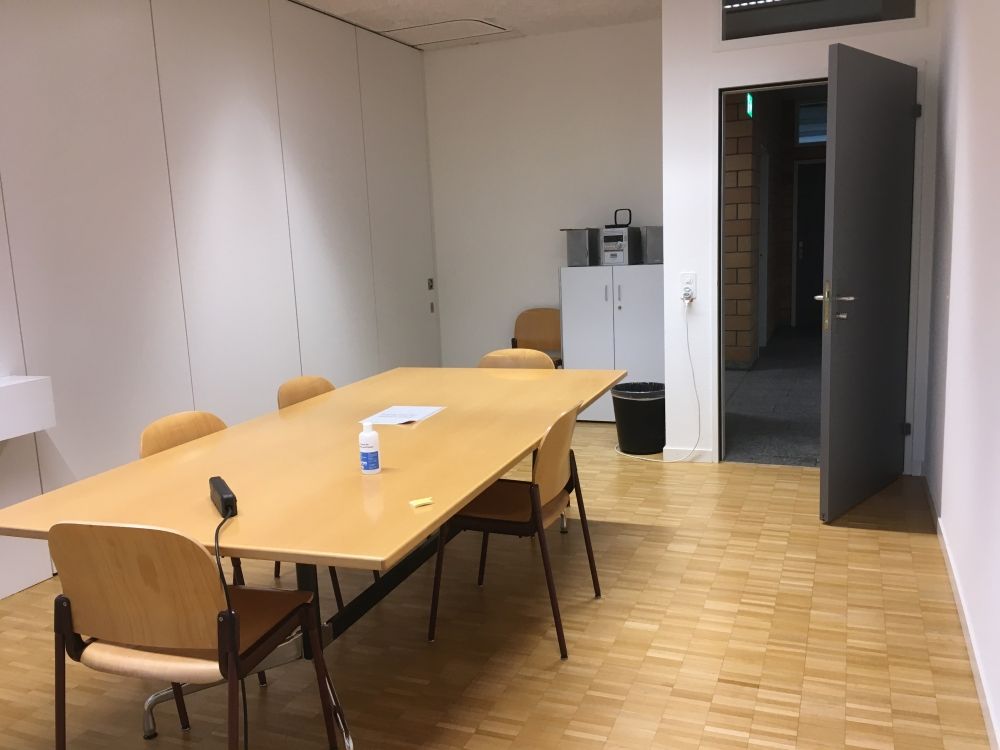 Sitzungsraum PLM-H-309: Sitzungsraum mit Rücken zu den Fenstern gegenüber der Tür.