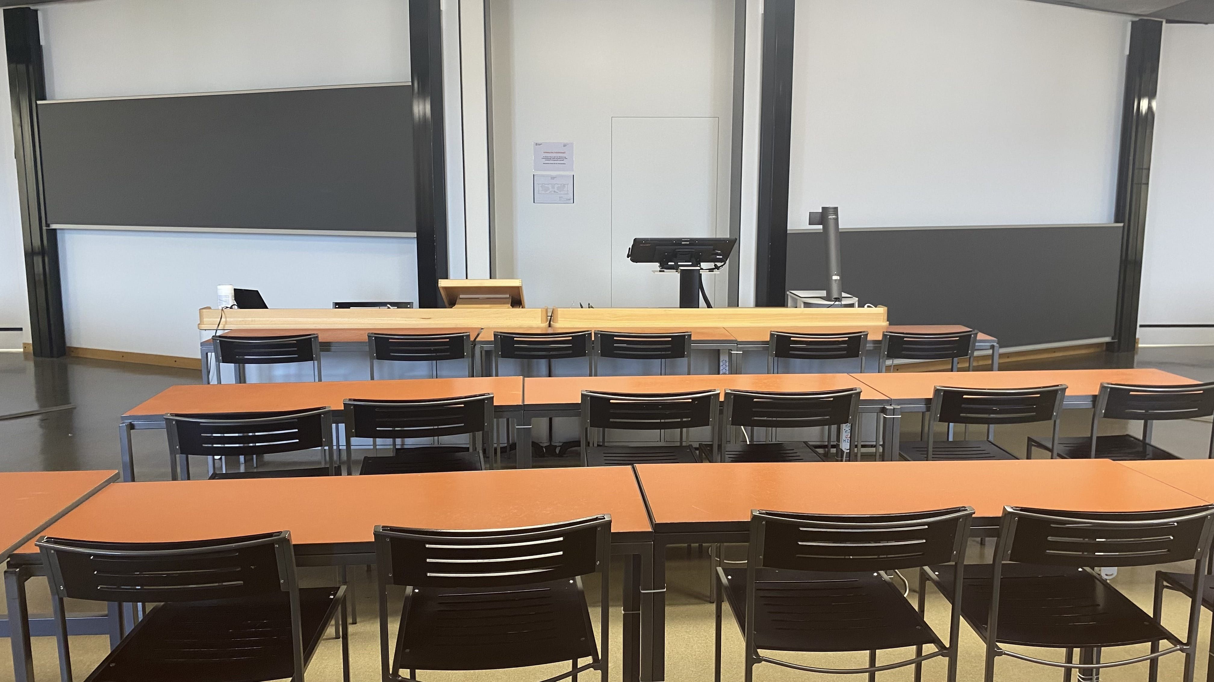 Hörsaal KOL-H-312a: Ansicht zum Dozierendenpult hin von der mittleren Sitzreihe aus.