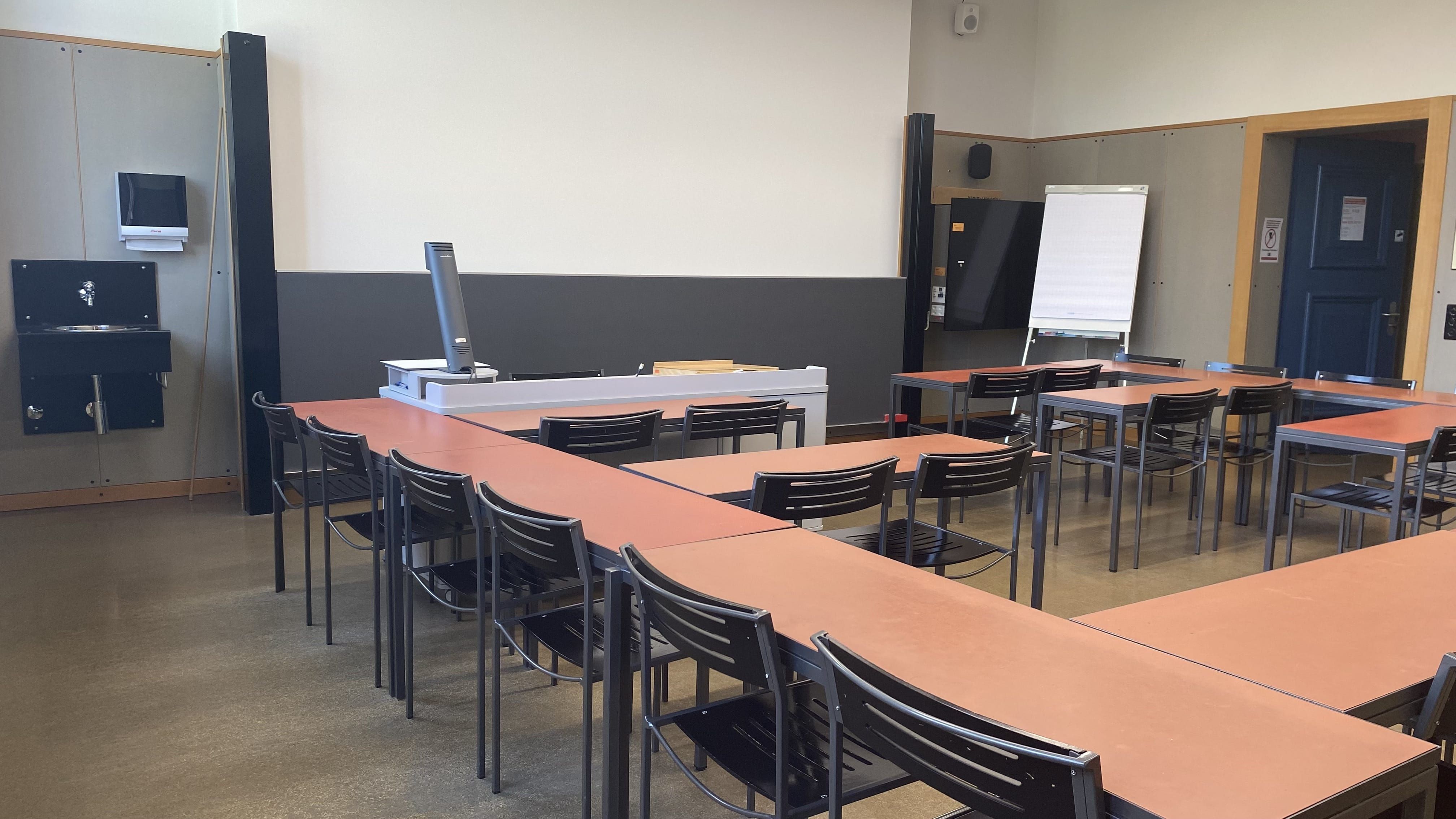 Seminarraum KOL-H-320: Ansicht zum Dozierendenpult. Die Eingangstür befindet sich rechts im Bild.