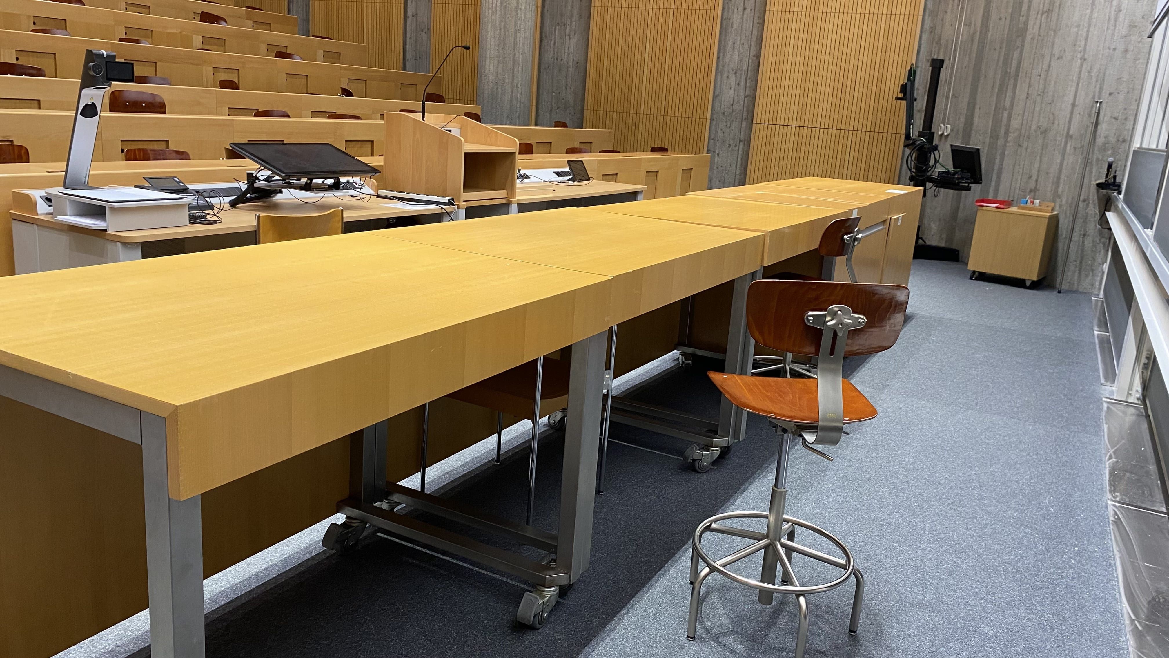 Hörsaal Y24-G-55: Ansicht auf die Tische hinter dem Dozierendenpult.