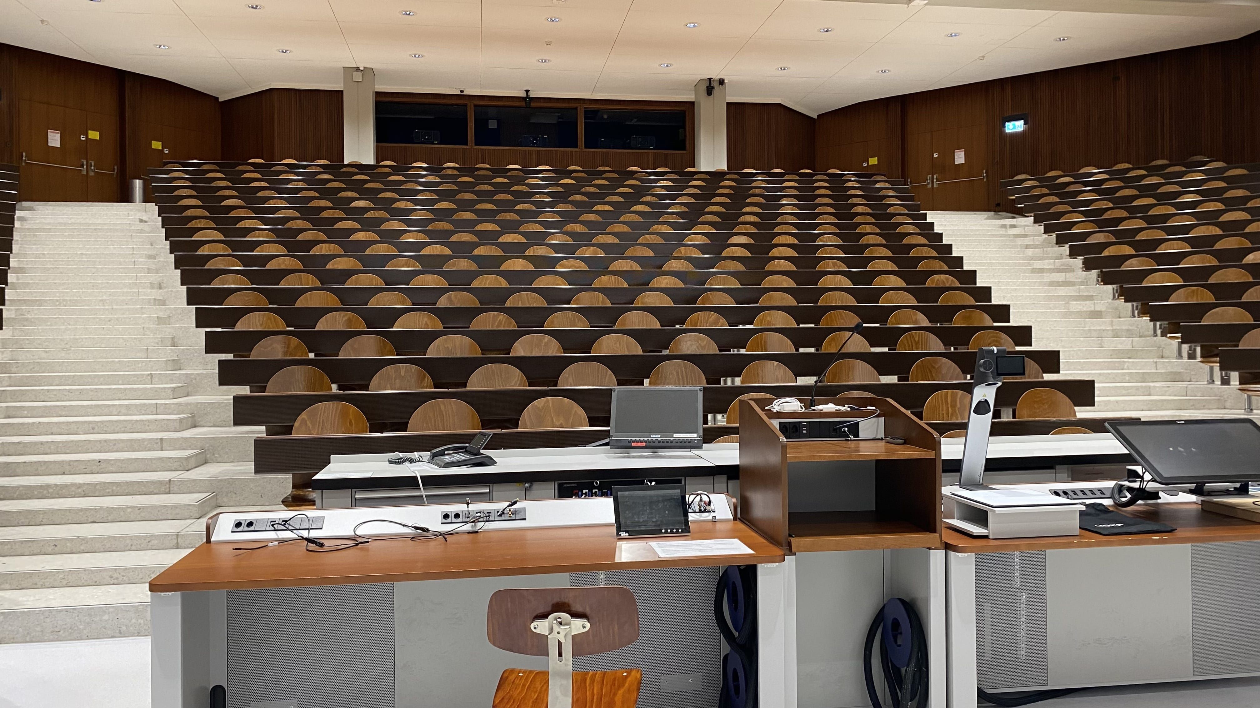 Hörsaal Y04-G-30: Ansicht auf die mittleren Sitzreihen. In diesem Segment befinden sich in der hintersten Reihe vier Tische mit Rollstuhl-Signet.