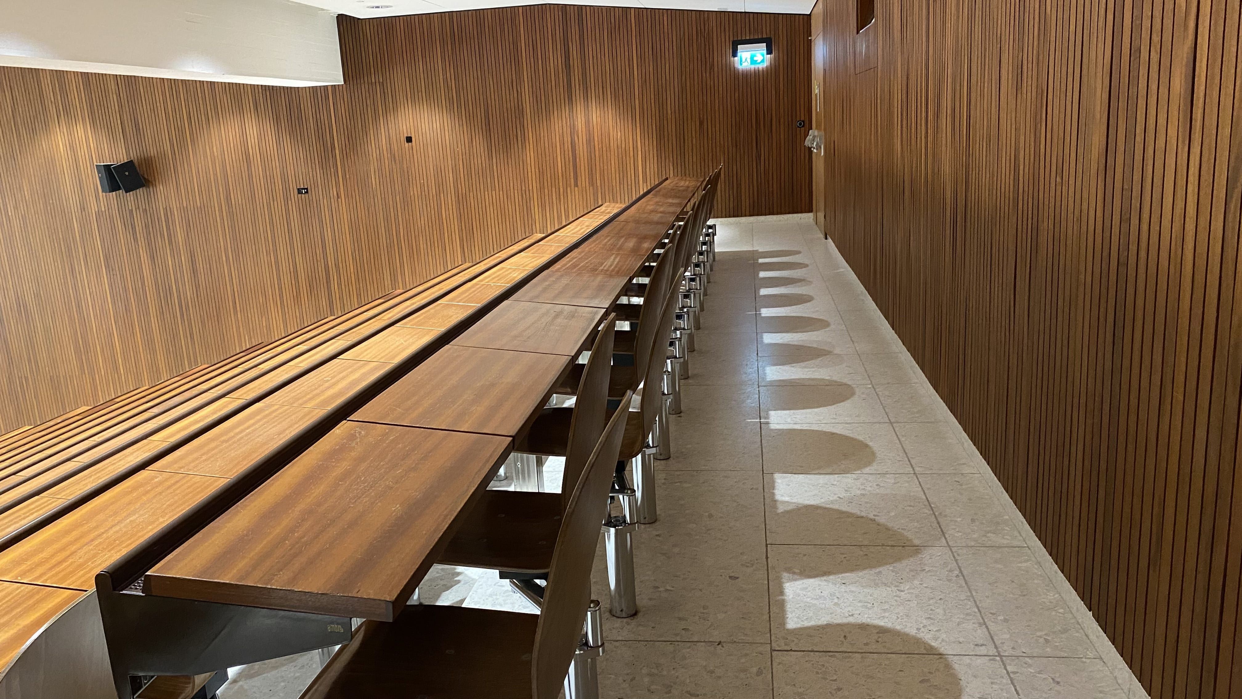 Hörsaal Y15-G-20: Ansicht auf die hinterste Sitzreihe. Es gibt nur Tische mit Fixbestuhlung.