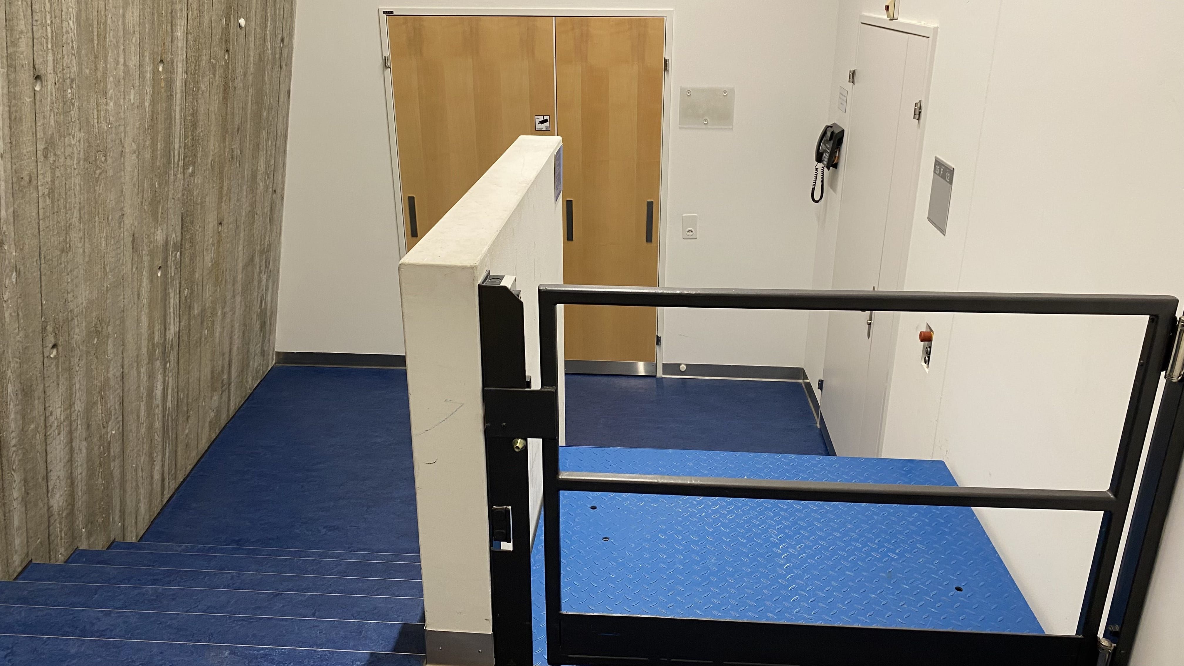 Seminarraum Y35-F-32: Ansicht auf den Zugang zur stufenlosen Eingangstür. Eine Hebebühne befindet sich rechts neben der Treppe.