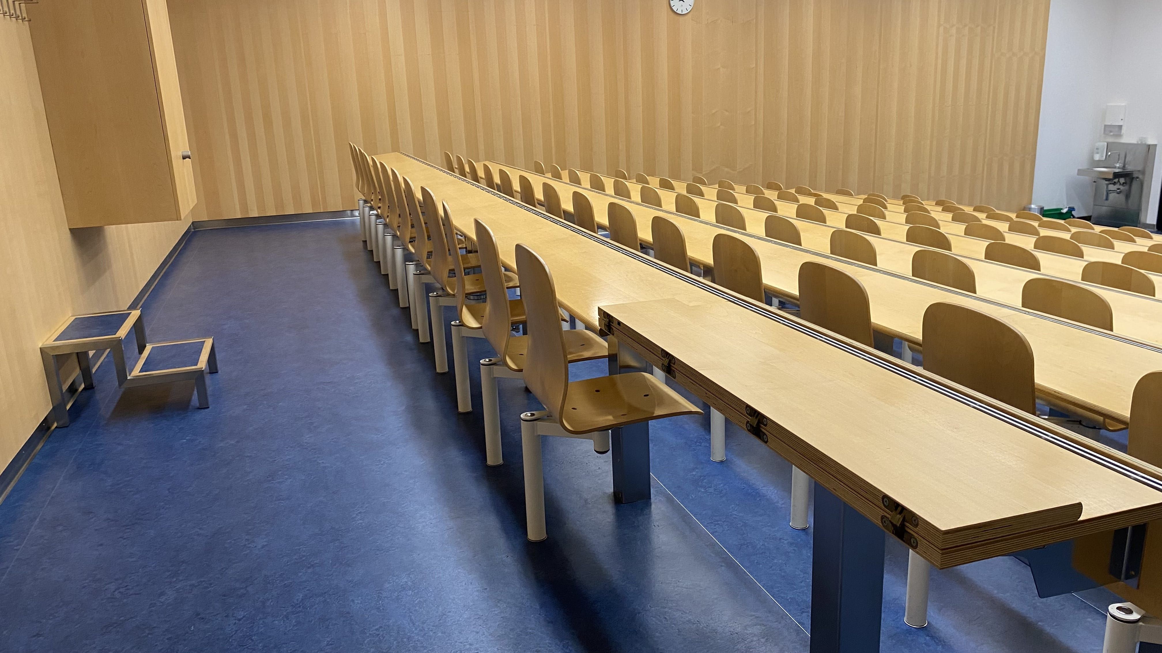 Seminarraum Y35-F-32: Ansicht auf die hinterste Reihe. Ein Tisch rechts aussen ist aufklappbar und hat keine fixe Bestuhlung.
