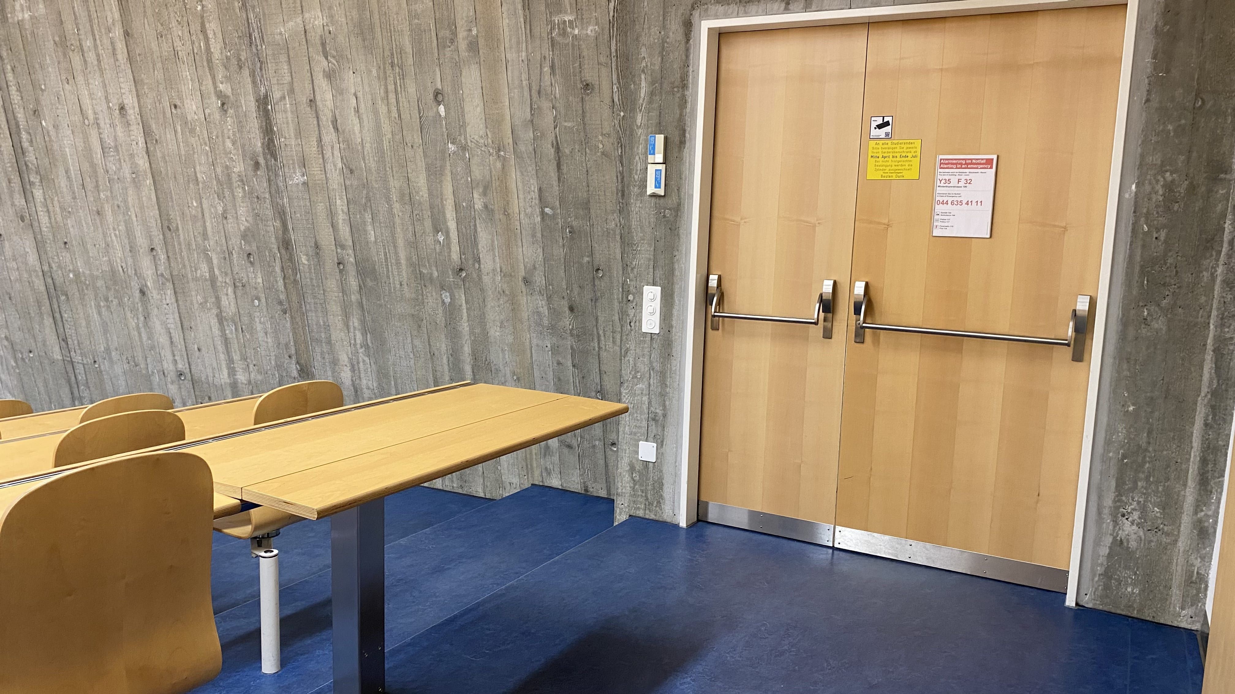 Seminarraum Y35-F-32: Ansicht auf die zweite, stufenlose Eingangstür. Gleich daneben - in der hintersten Reihe rechts aussen - befindet sich ein aufklappbarer Tisch ohne fixe Bestuhlung.