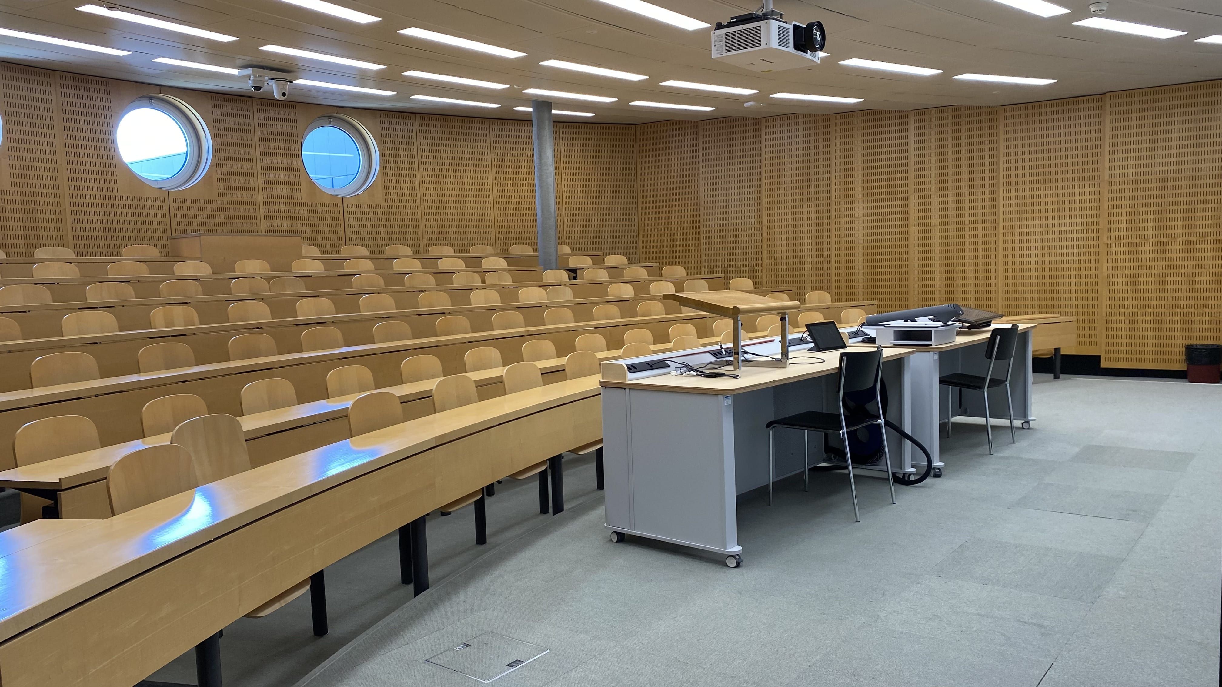 Hörsaal Y17-M-05: Ansicht auf den Raum von der linken Eingangstür aus. Es gibt eine Eingangstür ganz links im Raum und ganz rechts im Raum.