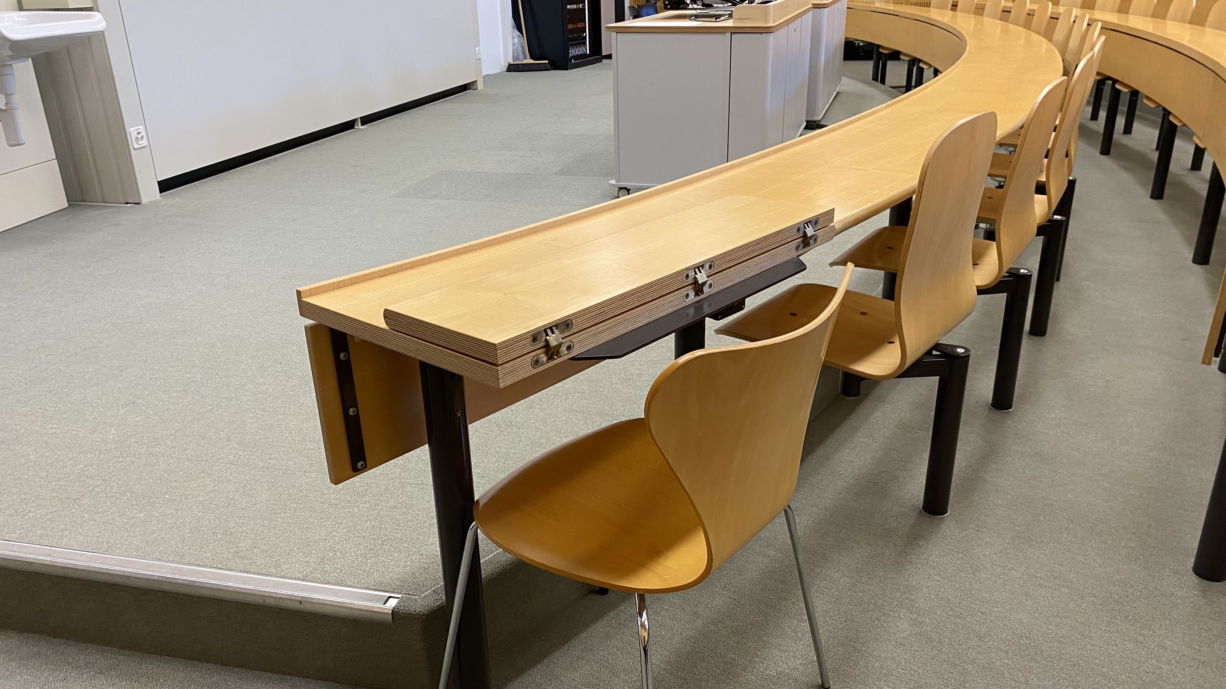 Hörsaal Y17-M-05: Ansicht auf einen von zwei ausklappbaren Tischen ohne fixe Bestuhlung. Dieser Tisch befindet sich in der vordersten Reihe ganz rechts und ist stufenlos über die rechte Eingangstür erreichbar.