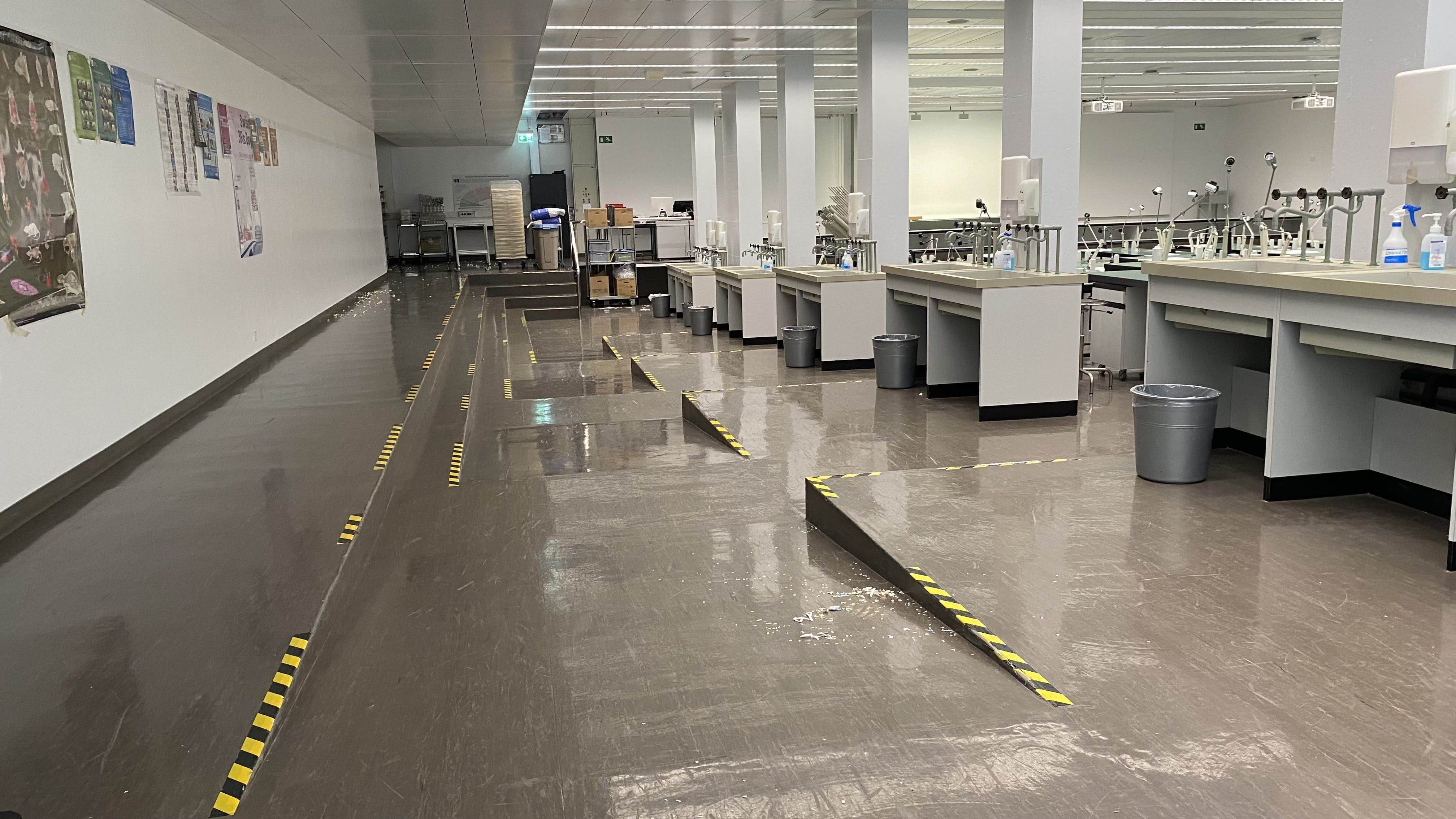 Praktikumsraum Y14-F-21: Ansicht auf den Raum von der Eingangstür aus. Eine Rampe führt von der Tür stufenlos bis ans Ende des Raumes und zwischen die Sitzreihen.