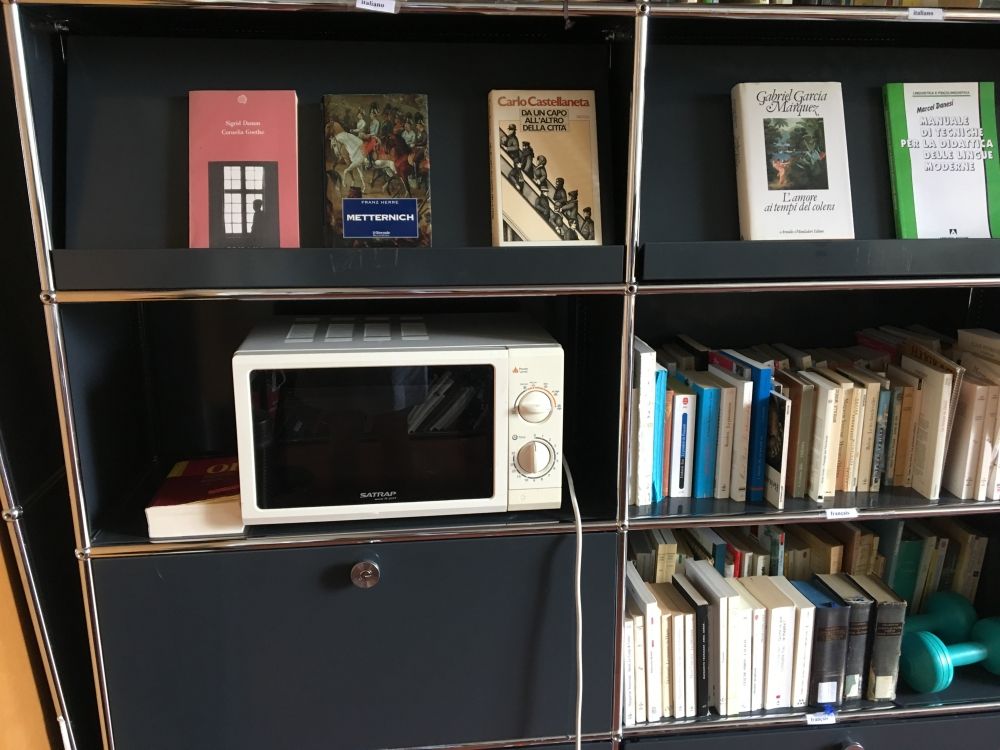 Arbeitsraum für Studierende ZUG-G-51A: Blick nach links von der Eingangstür. Eine Mikrowelle befindet sich auf dem Bücherregal.