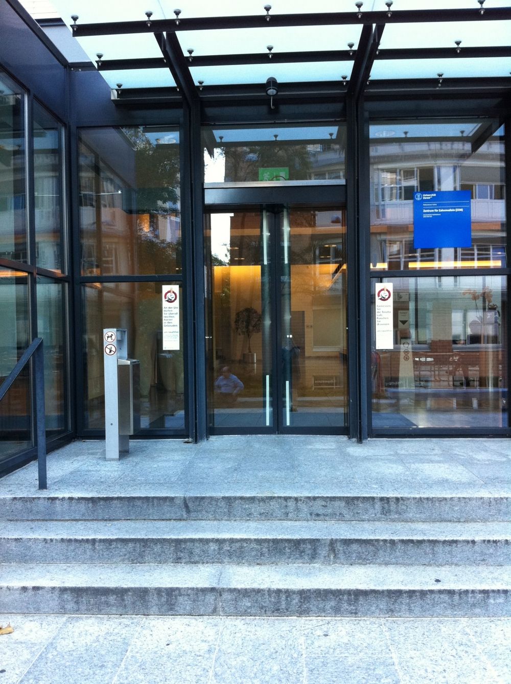 Gebäude ZUI: Sicht auf den Haupteingang mit seinen drei Stufen und der automatischen Schiebetür.