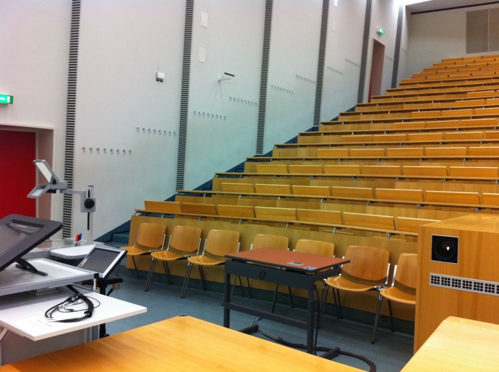 Hörsaal SOD-1-102: Zuvorderst befindet sich ein elektrisch höhenverstellbares Pult mit Rollstuhl-Signet.