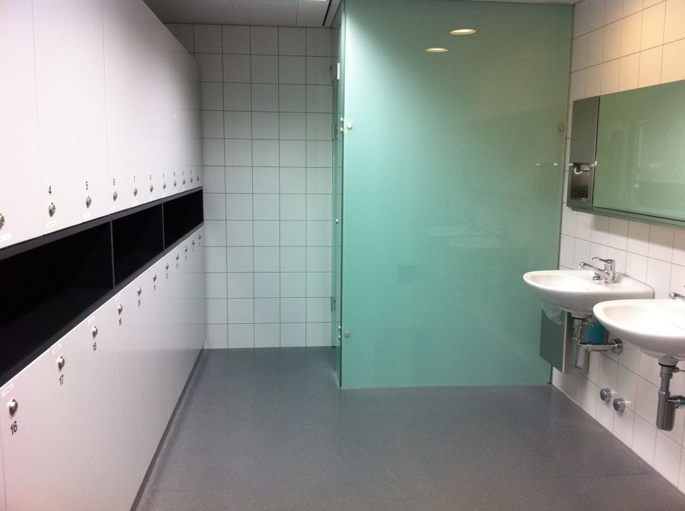 Umkleide- und Waschraum ZUI-C-13A: Raum mit Sicht auf die Schliessfächer (links) die Dusche (hinten rechts) und die beiden Lavabos (vorne rechts).
