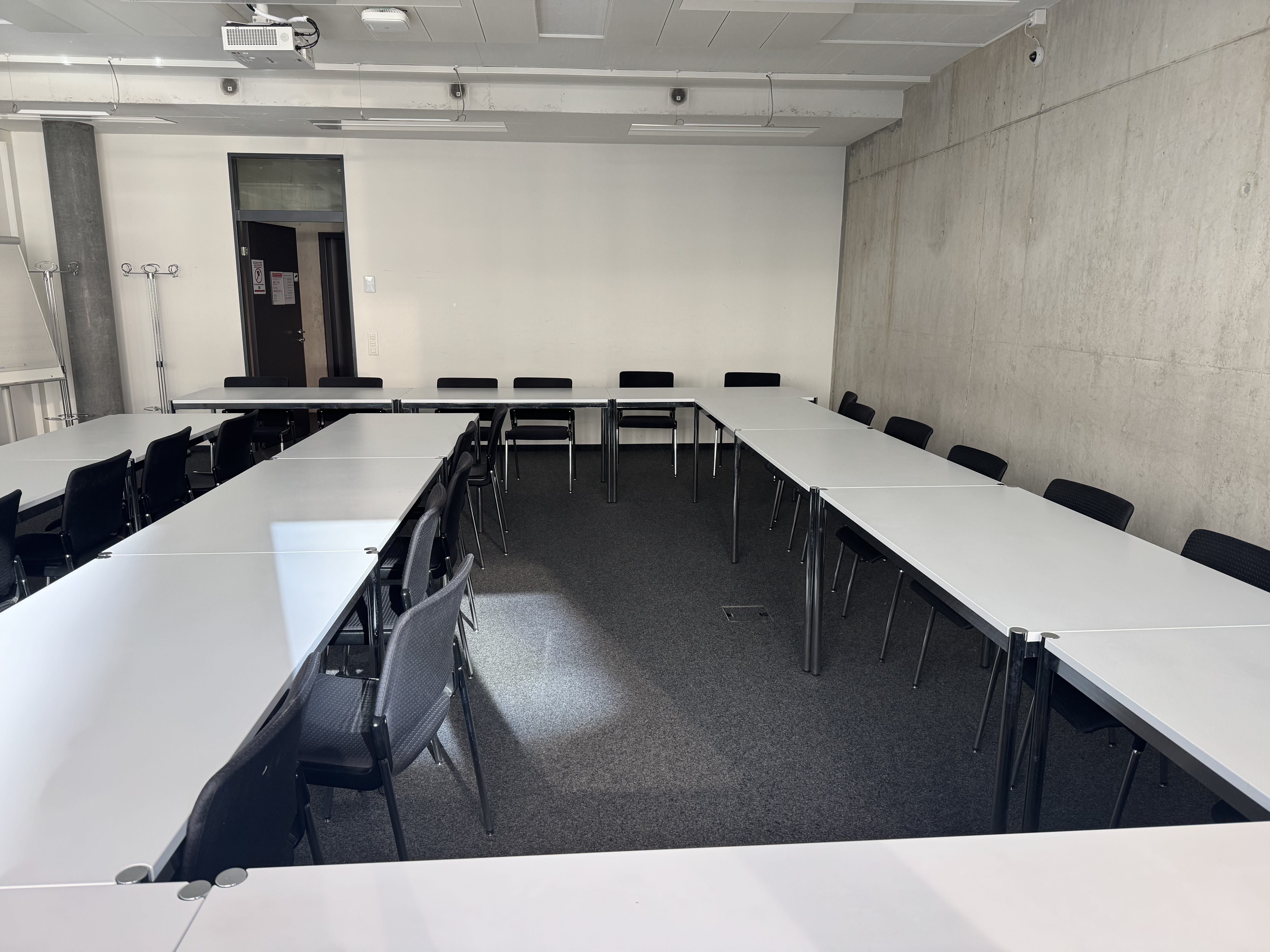 Seminarraum AND-02-02: Ansicht zur Eingangstüre hin. Stuhlreihe mit viel Platz nach hinten.