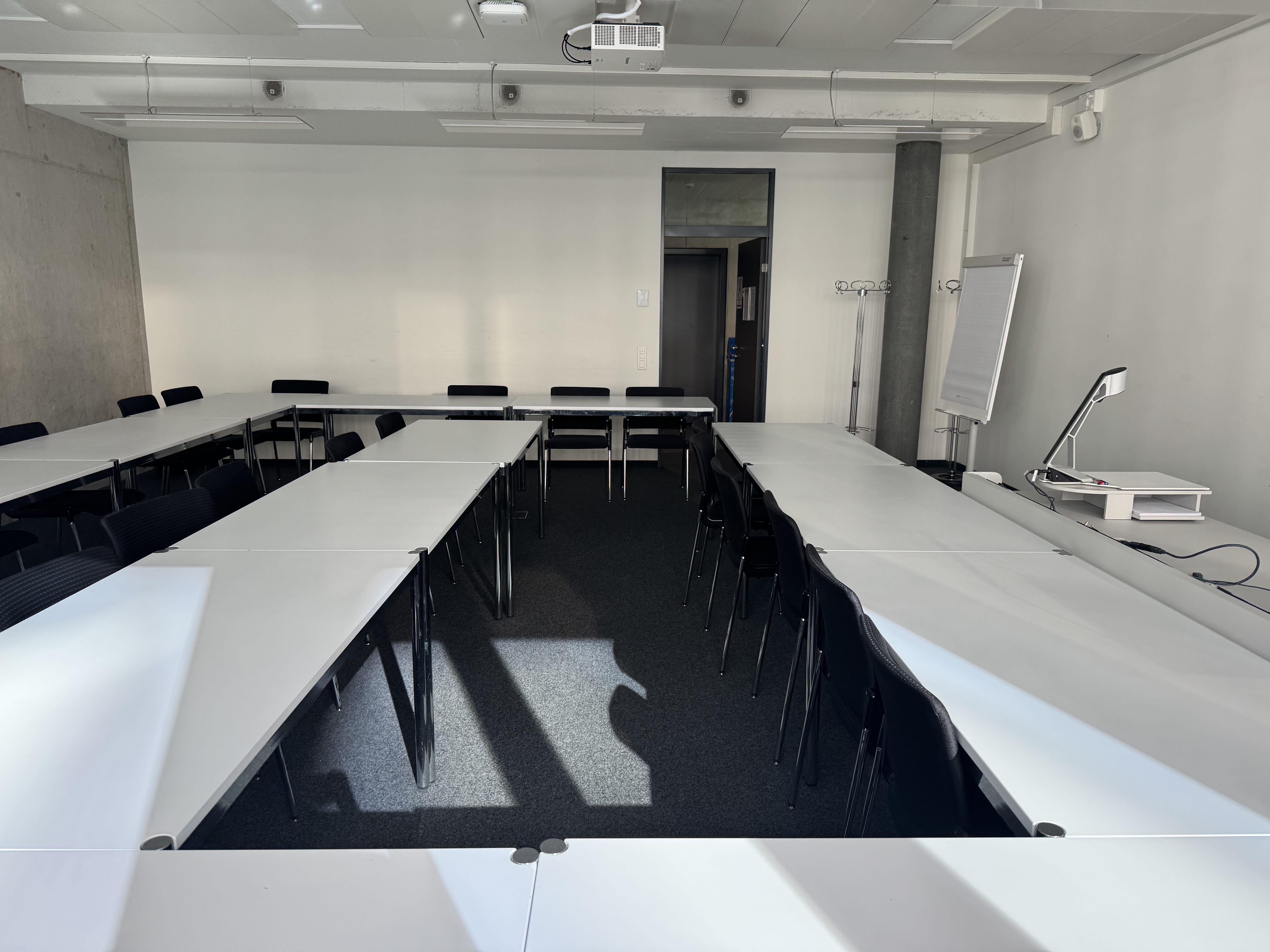 Seminarraum AND-2-06: Ansicht zur Eingangstüre hin. Stuhlreihe mit viel Platz in der Mitte.