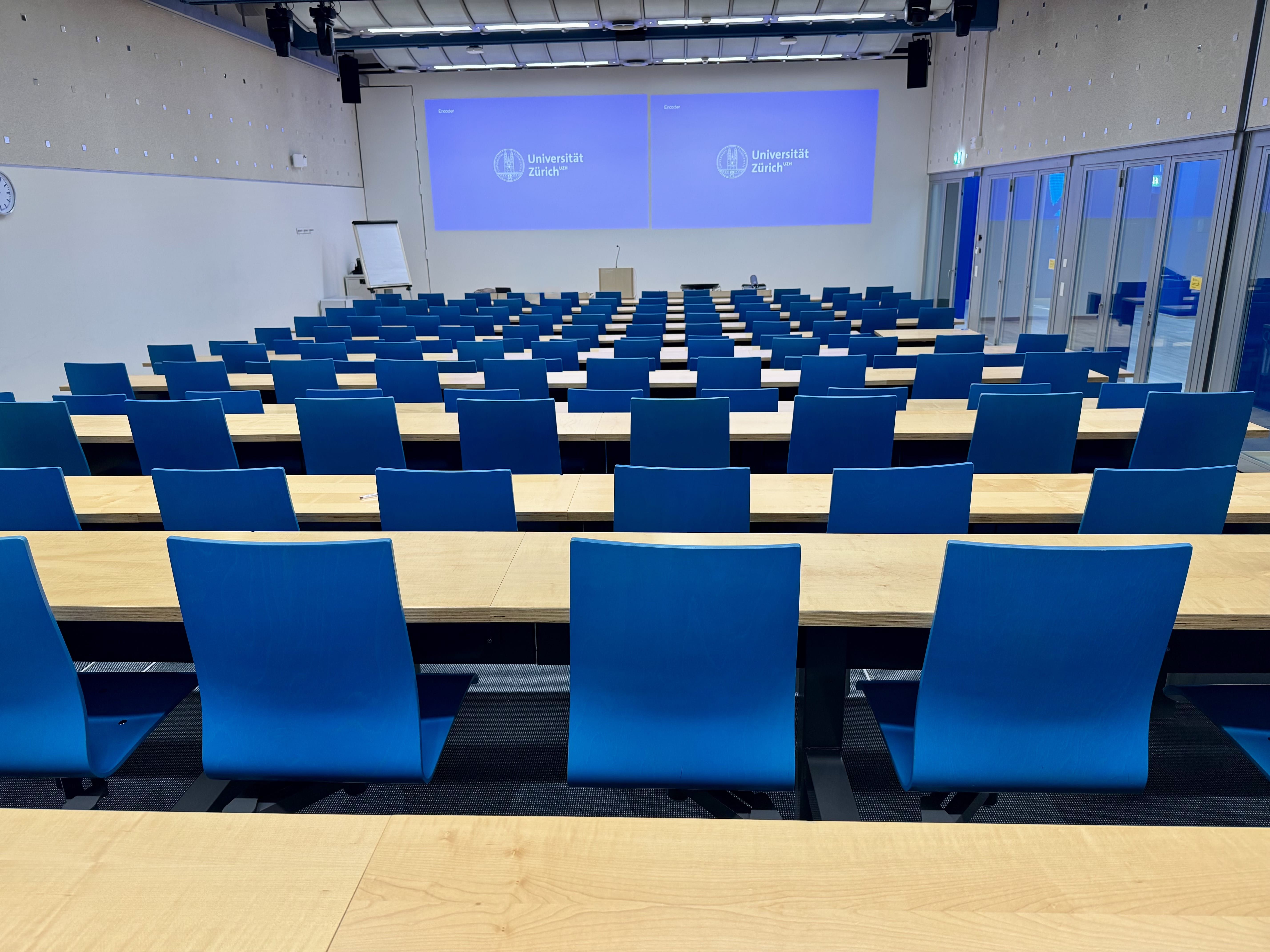 Hörsaal BIN-0-K.02: Ansicht auf den Raum zum Dozierendenpult hin. Die Eingangstür befindet sich rechts.