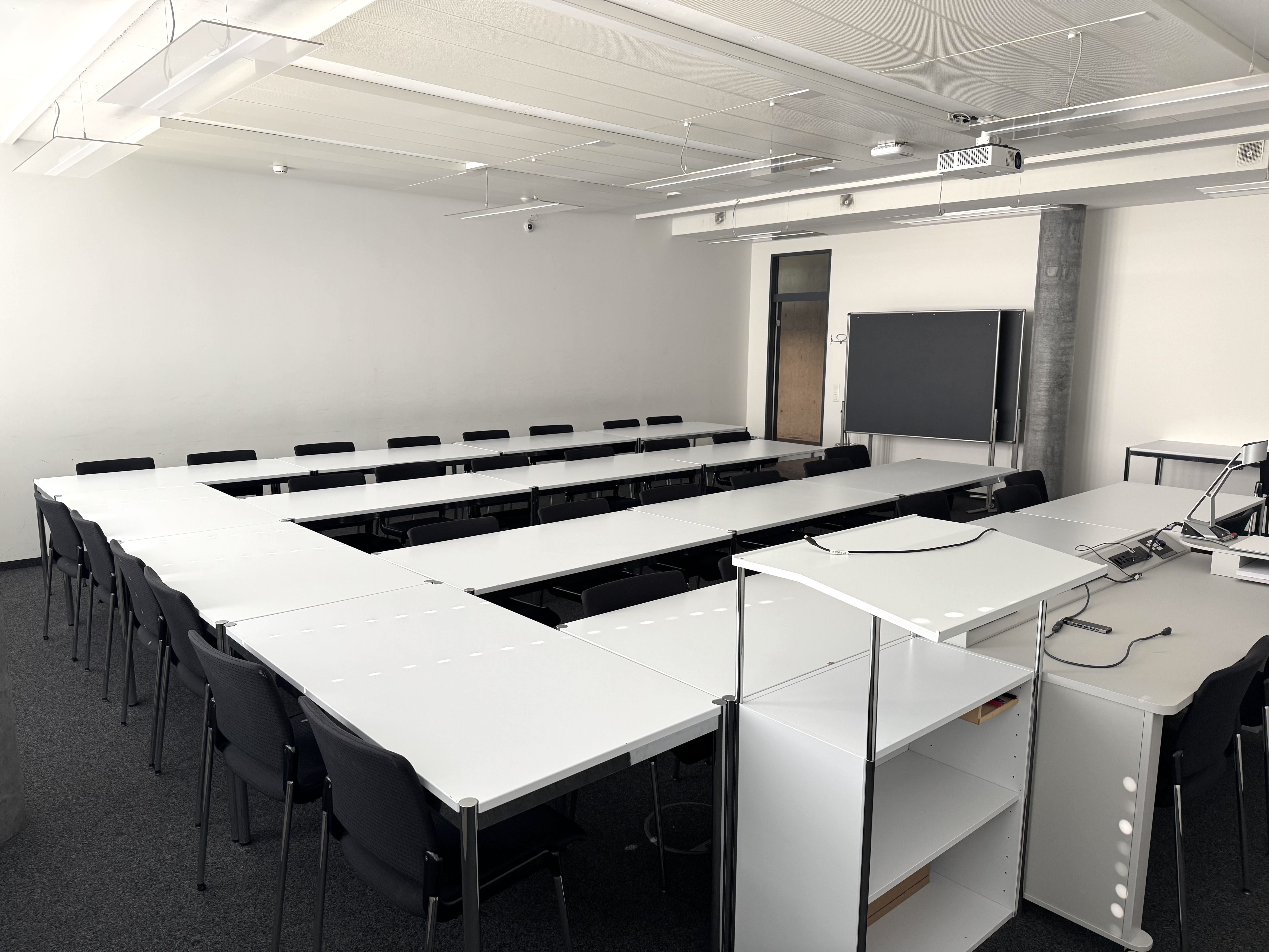 Seminarraum AND-03-44: Ansicht auf den Raum von Dozierendenpult aus. Die Eingangstüre befindet sich in der Mitte des Bildes.