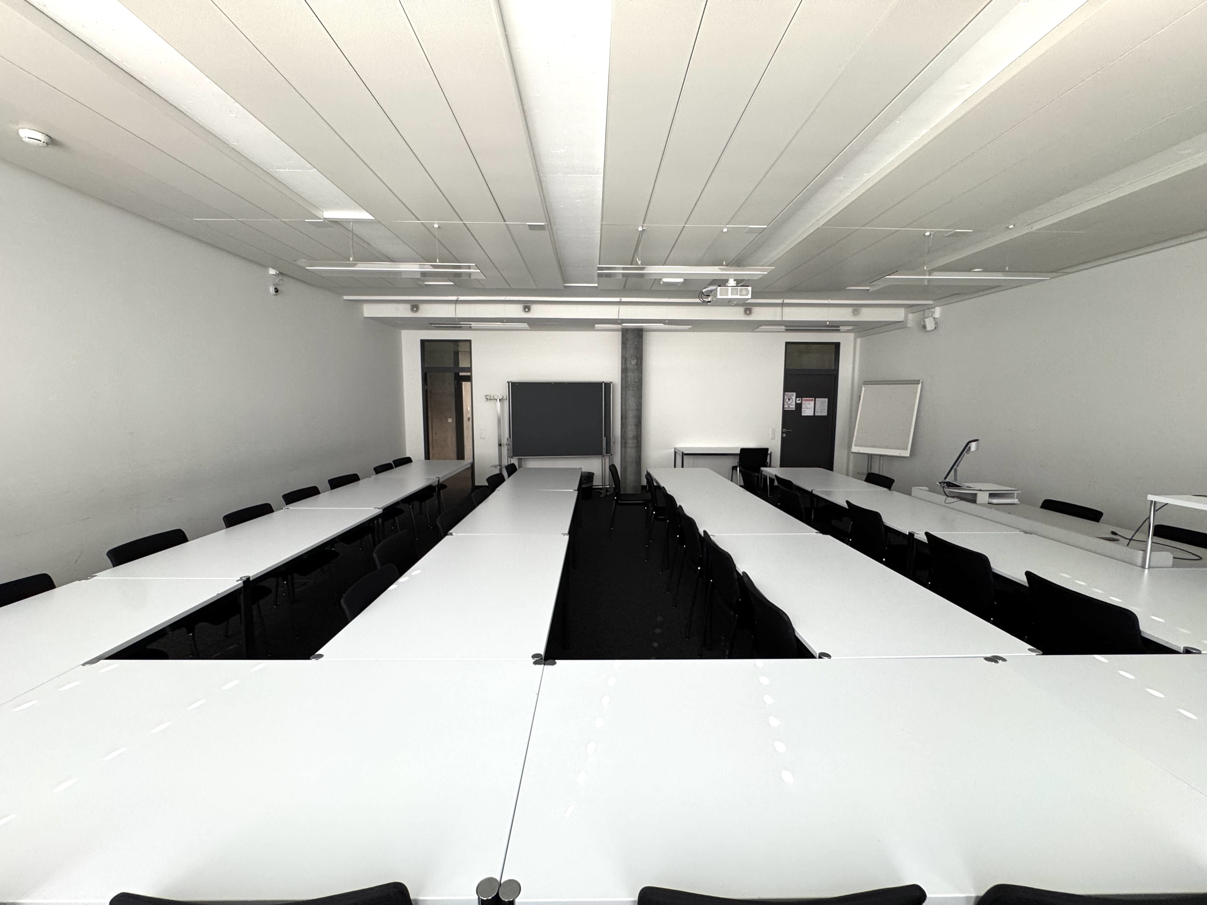 Seminarraum AND-03-44: Ansicht auf die mittleren Stuhlreihen zur Eingangstüre hin.