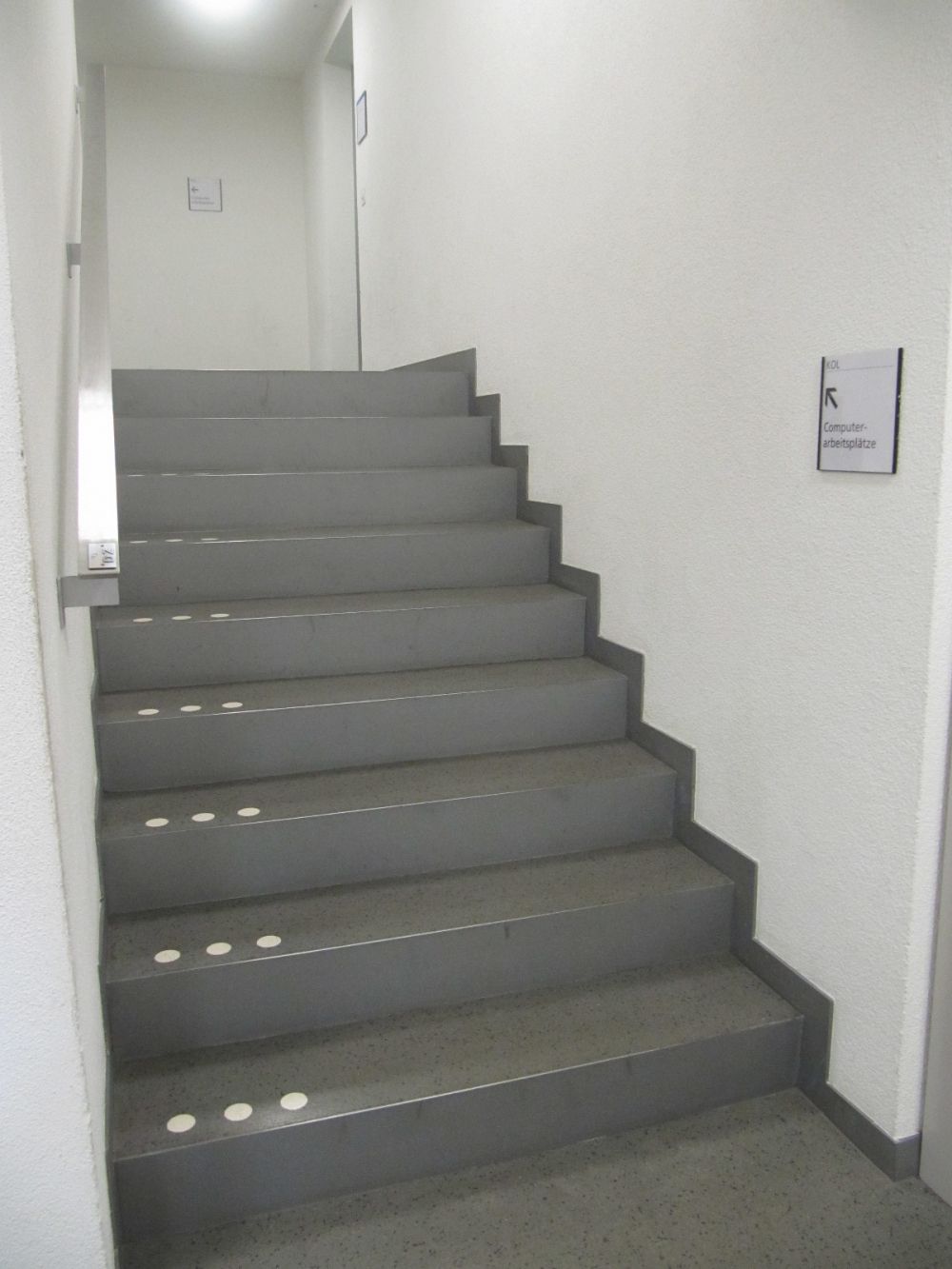 KOL, Stockwerk Da: Nächste Treppe links um die Ecke, welche auf das Stockwerk Kol-Da führt, mit Handlauf, Stockwerkbezeichnung und Bodenmarkierung.