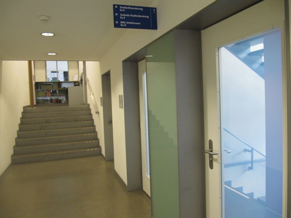 KOL, Stockwerk Ea: Oben links ist der Eingang von der Türe KOL-E-49. Hier beim blauen Schild rechts das Treppenhaus benützen, um ins Zwischenstockwerk KOL-Ea zu gelangen.