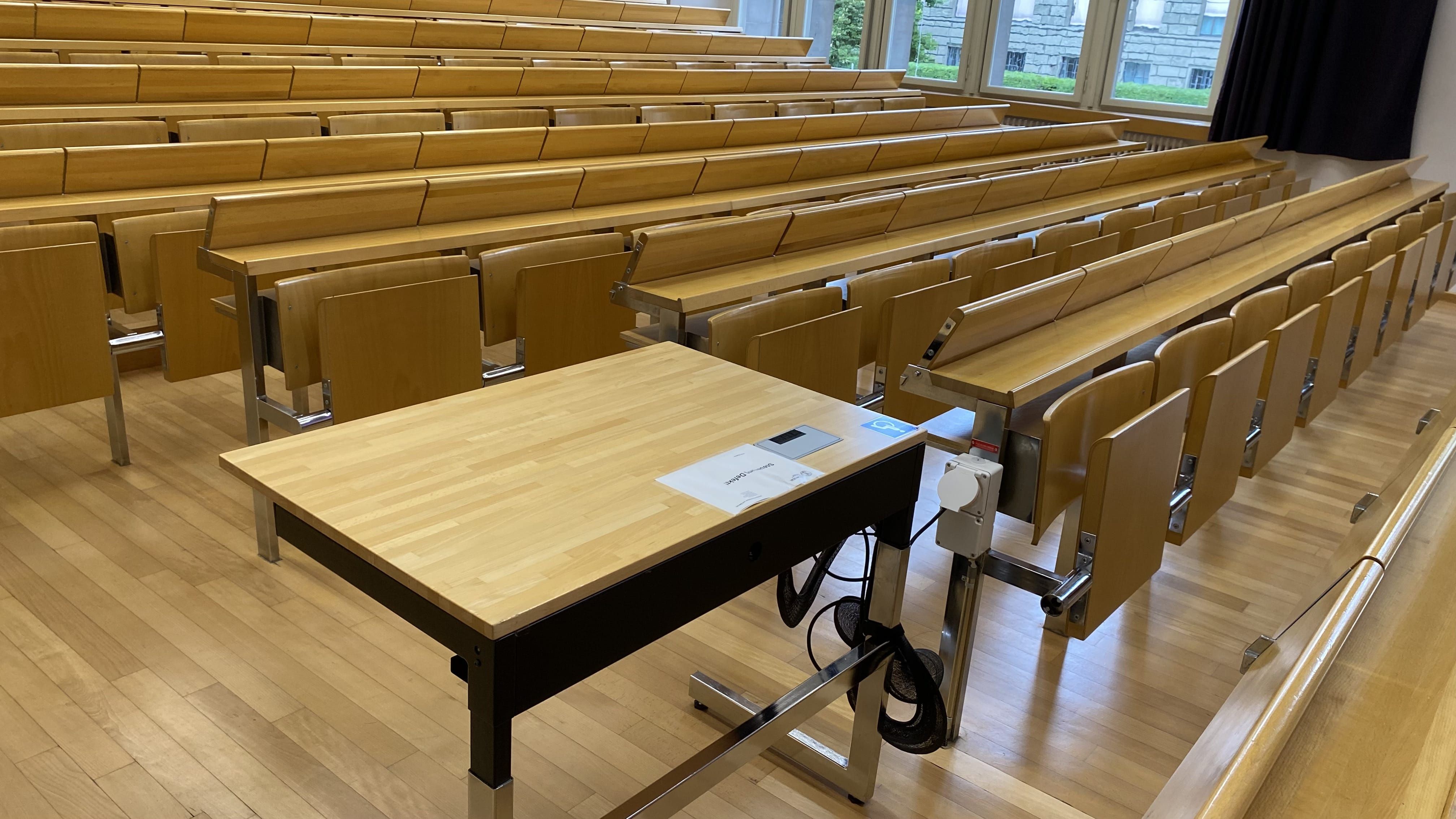Hörsaal KO2-F-150: Nahansicht auf den Tisch mit Rollstuhl-Signet.