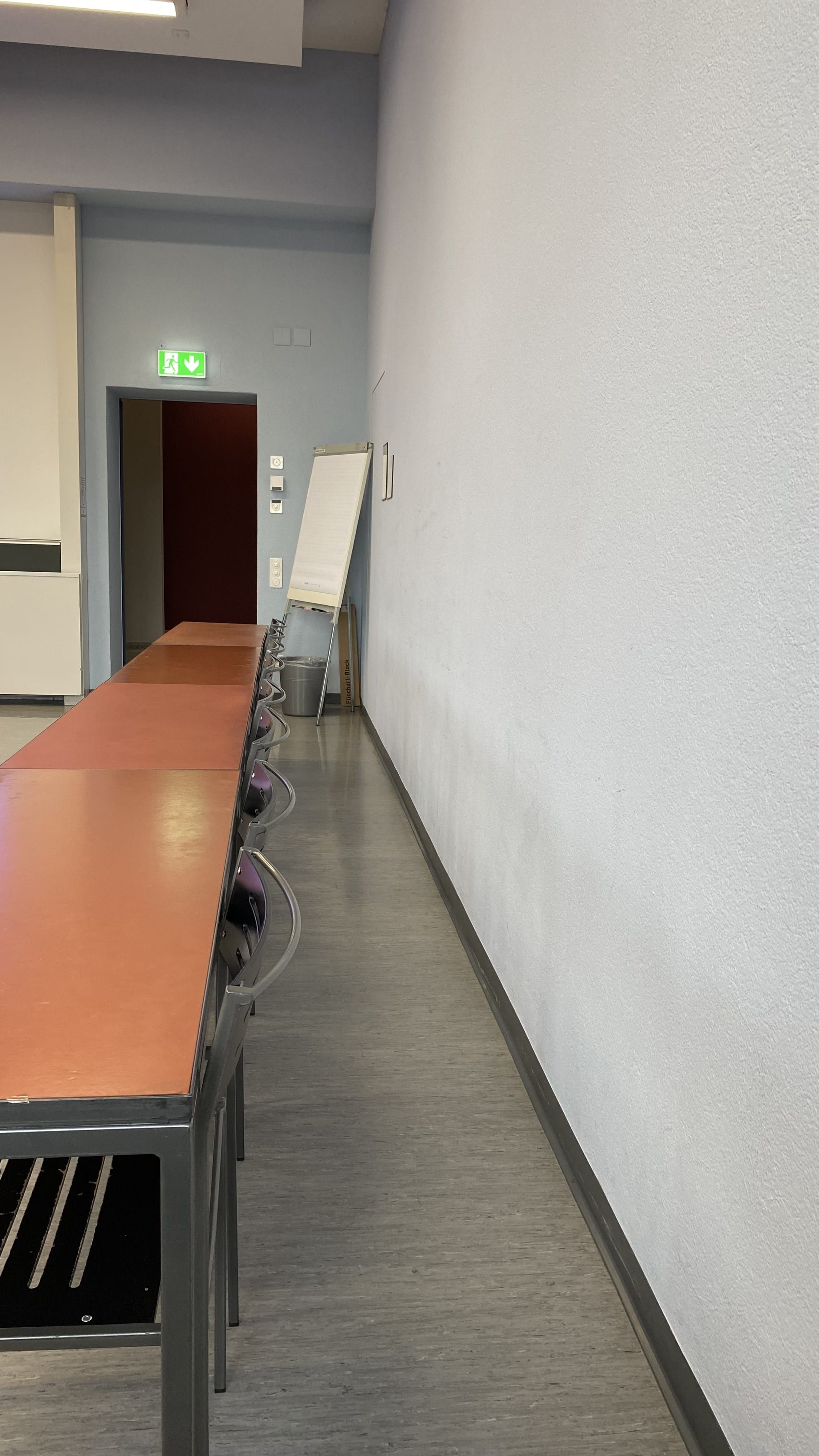 Seminarraum KO2-D-54: Ansicht auf den schmalen Durchgang zur Eingangstüre hin.